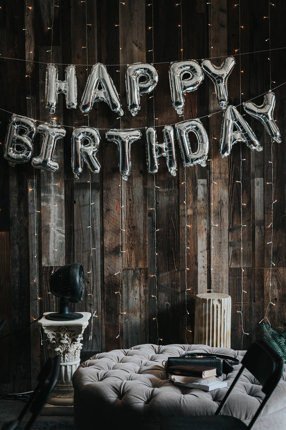 happy birthday氣球掛在帶有燈串的木牆上。