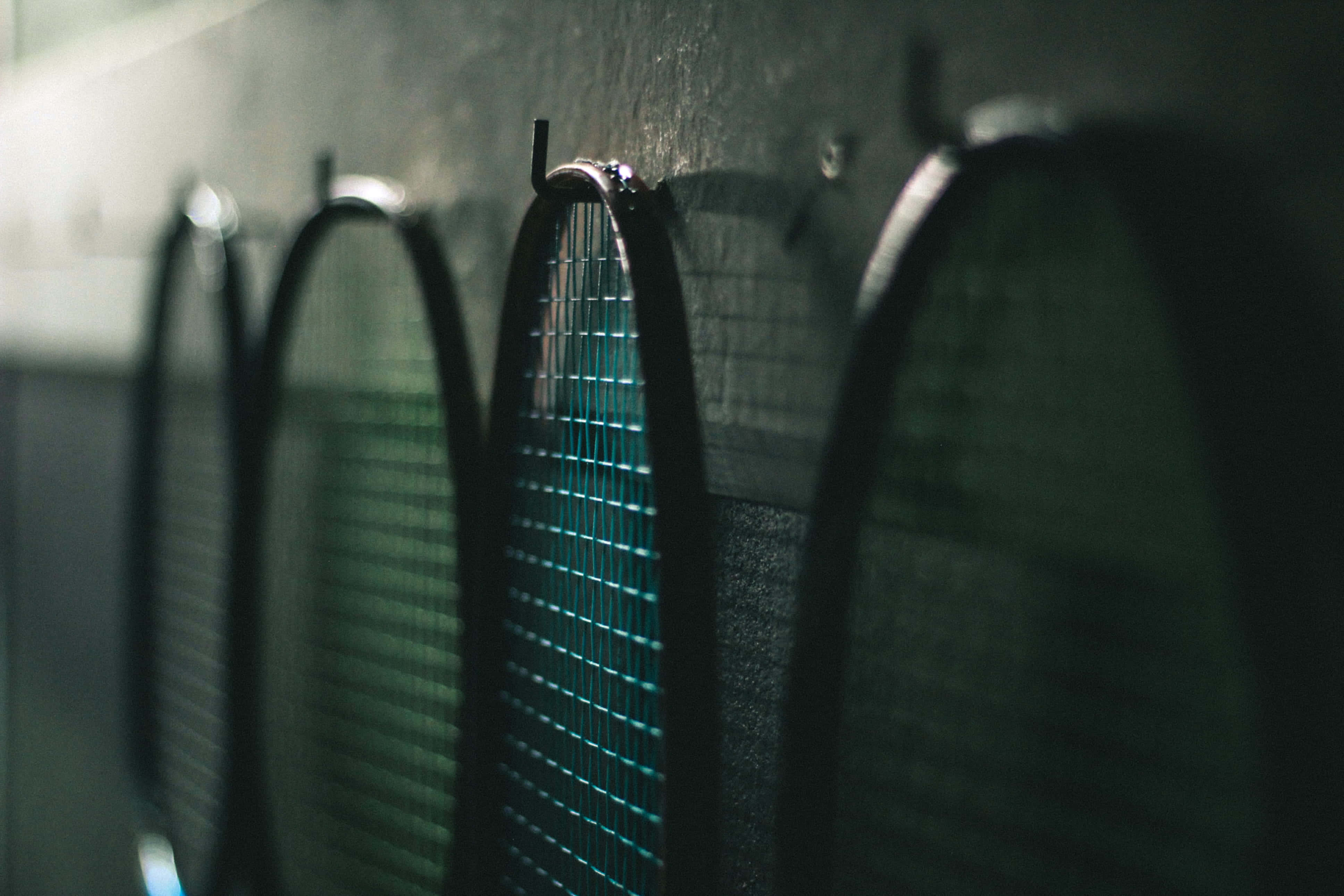 Badminton 桌布 壁紙 — 室內光線昏暗的網球場中，網球拍的特寫，景深較淺。