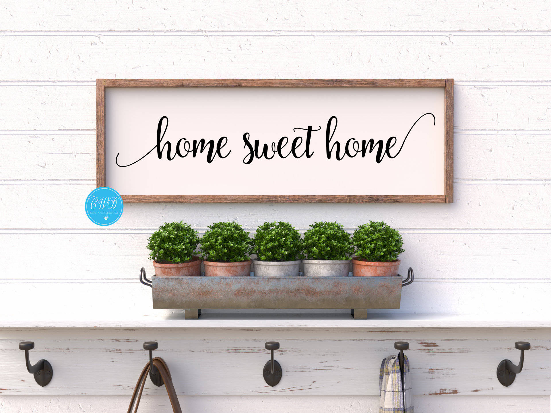家園甜蜜白色木牆 壁紙 — 一個寫著 home sweet home 的鄉村風格木牌掛在白色搭接牆上的一個金屬托盤上方，托盤裡有五盆黃楊。