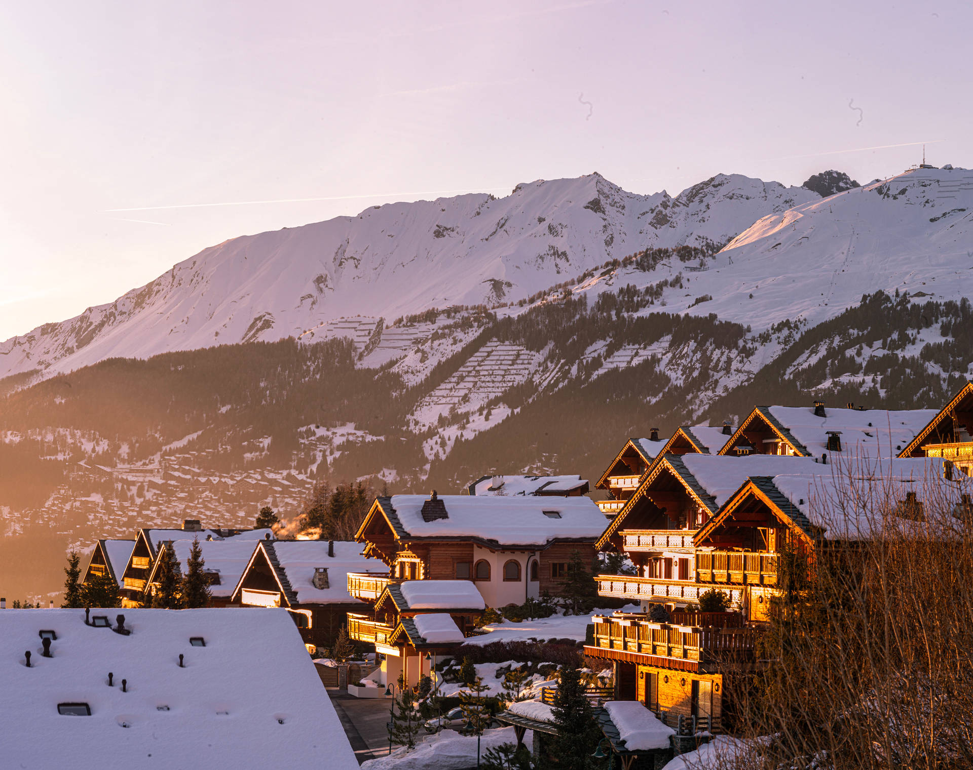 金色夕陽下阿爾卑斯山村莊的雪覆蓋小木屋。
