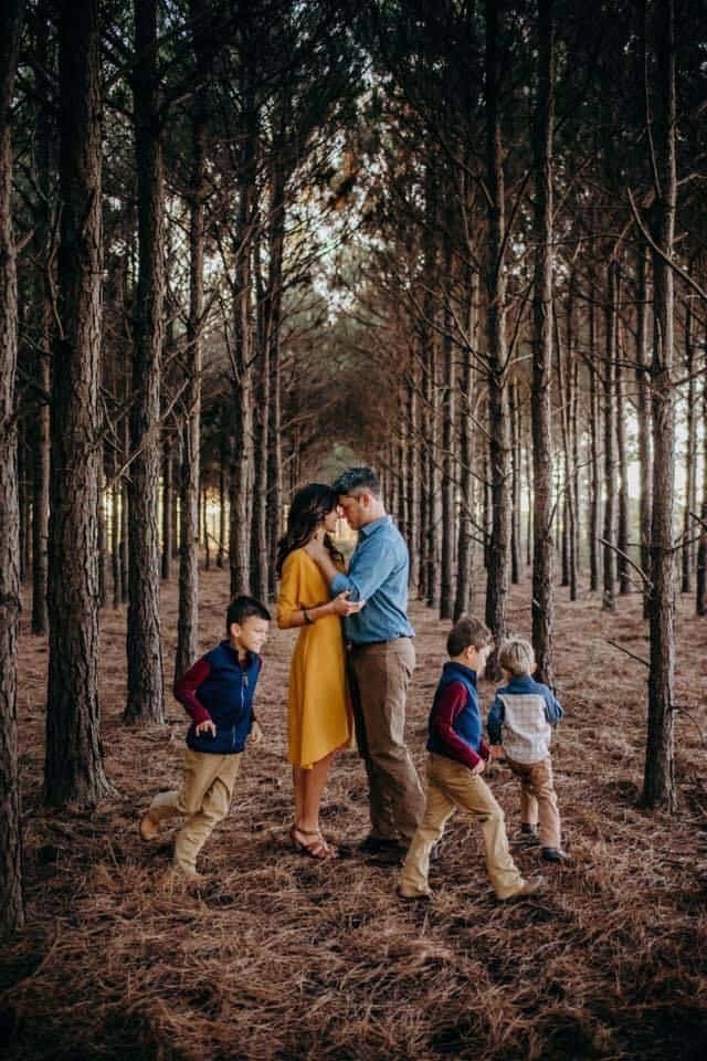 五口之家在松樹林中，斑駁的陽光。