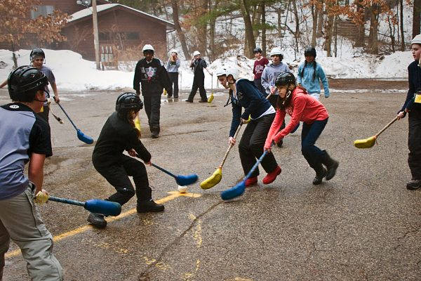 細路喺落雪嘅冬天戴住頭盔玩街頭曲棍球。