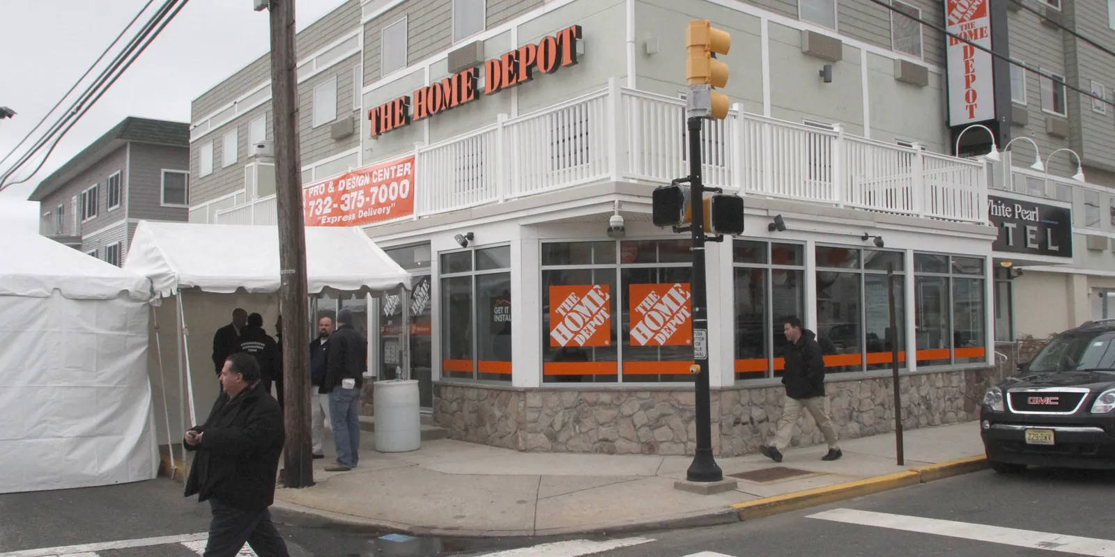 多雲天氣下，Home Depot商店角落有行人和停泊的汽車