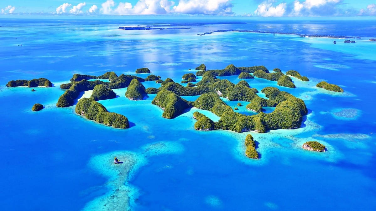 從高空俯瞰，熱帶島嶼在碧綠的海水中，陽光燦爛。