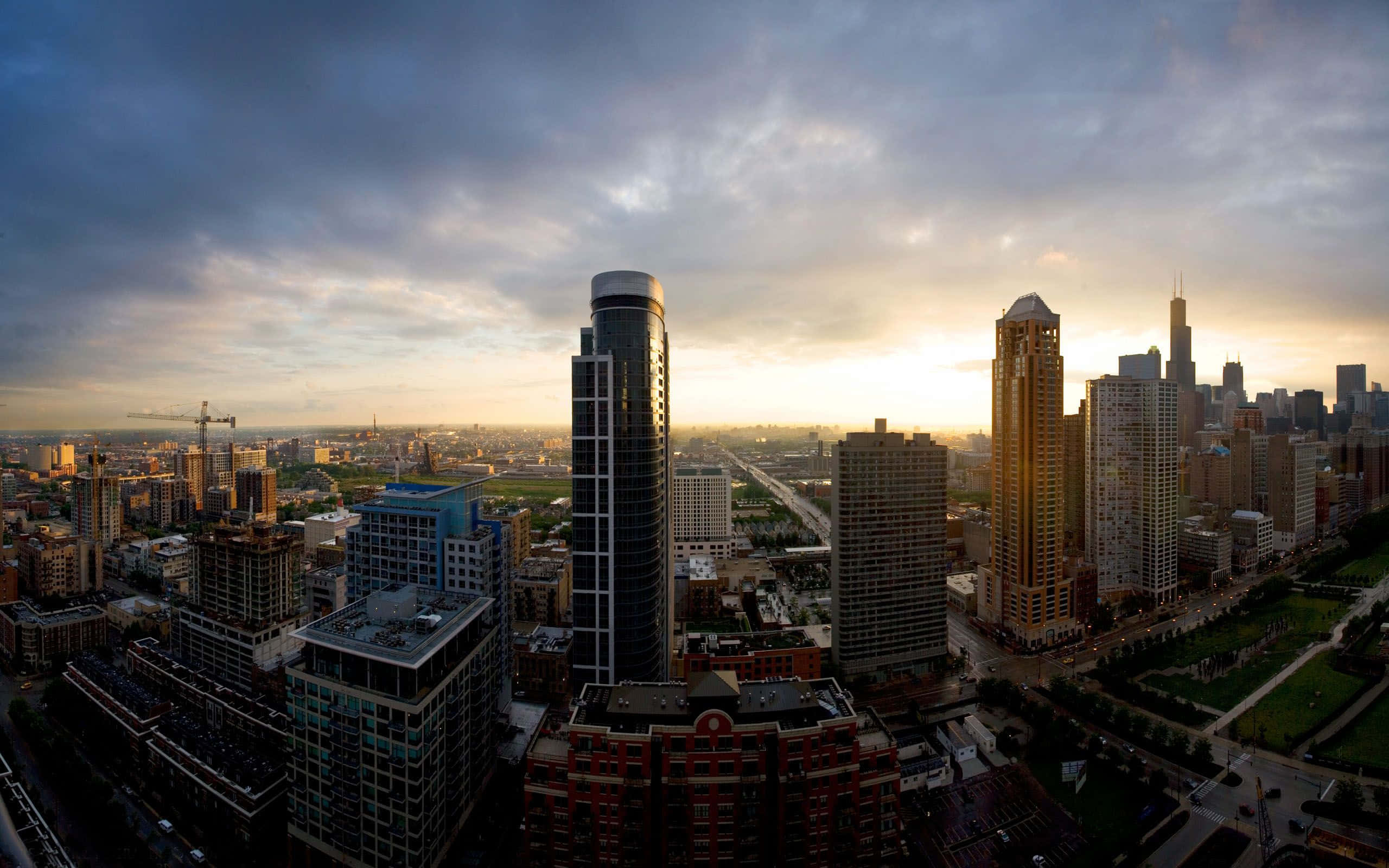 墨西哥 桌布 壁紙 — 密集城市天際線的 panoramic 日落景觀，高聳的摩天大樓和戲劇性的雲層投射出金色光芒。
