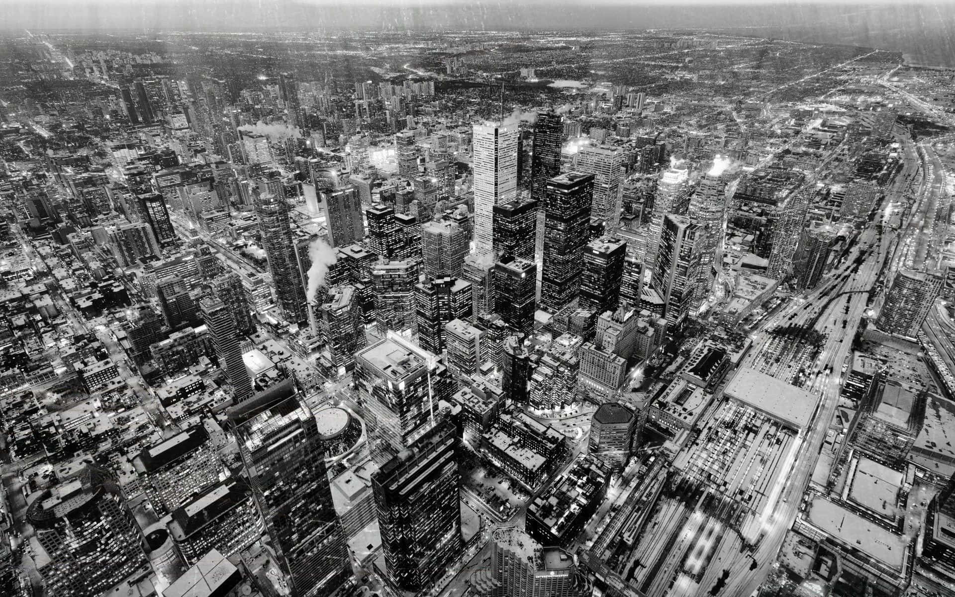 Black And White Cityscape 桌布 壁紙 — 密集城市天際線的黑白航拍視圖，高聳的摩天大樓和夜間發光的街燈。