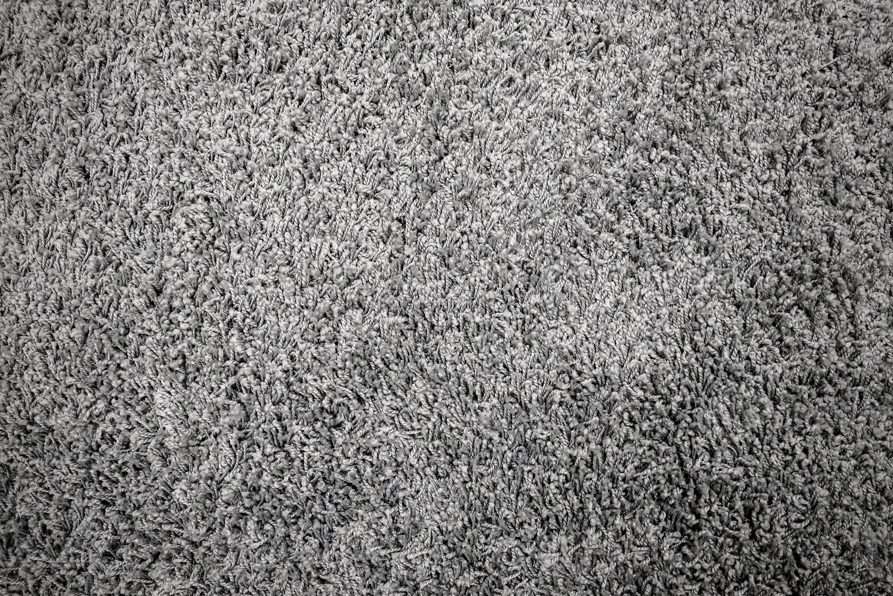 Carpet Texture 桌布 壁紙 — 密集灰色長毛地毯的特寫，帶有柔軟的質感纖維和微妙的燈光變化。