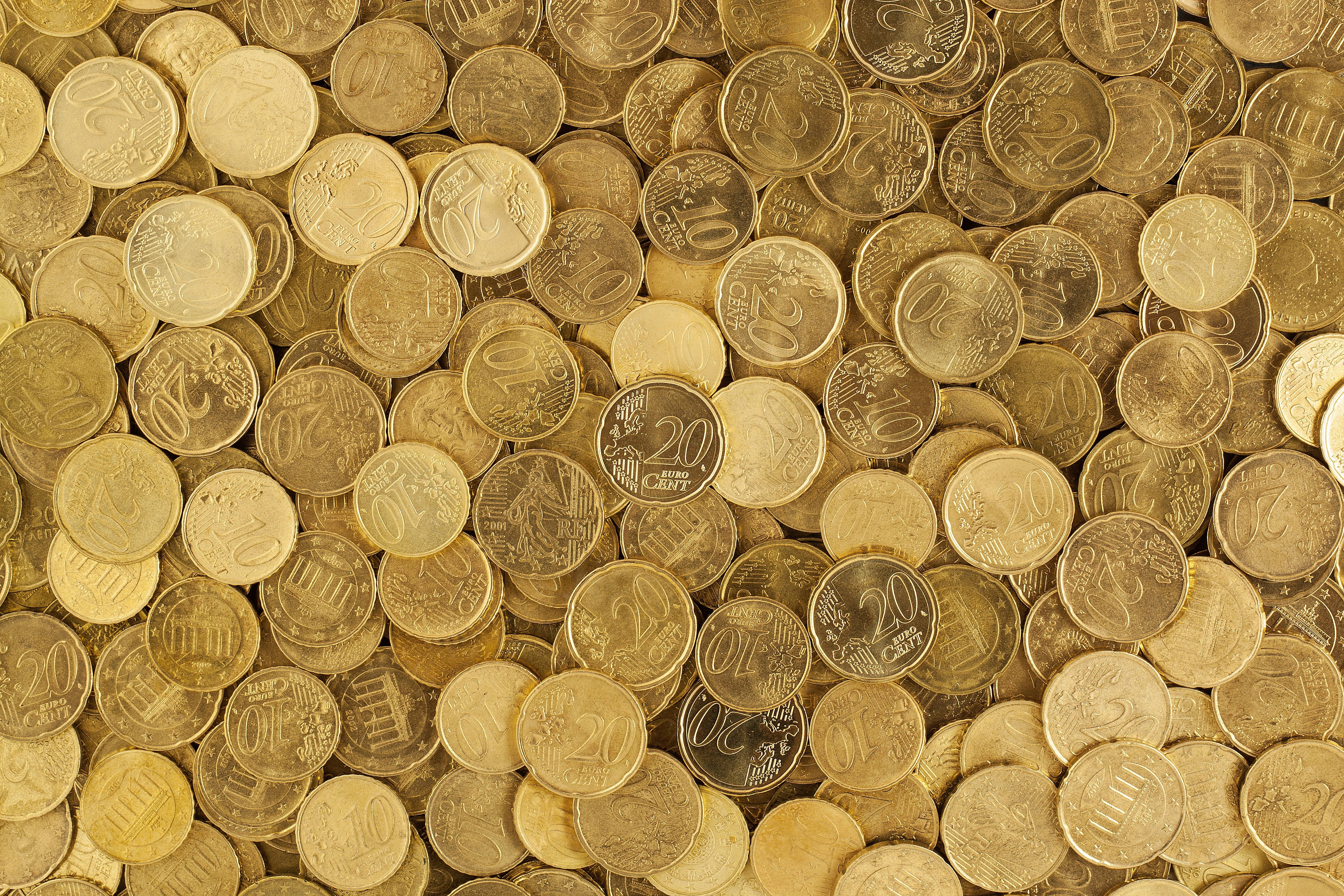 Money 桌布 壁紙 — 密集特寫散落的歐元硬幣，呈現溫暖金色色調，面額清晰可見。