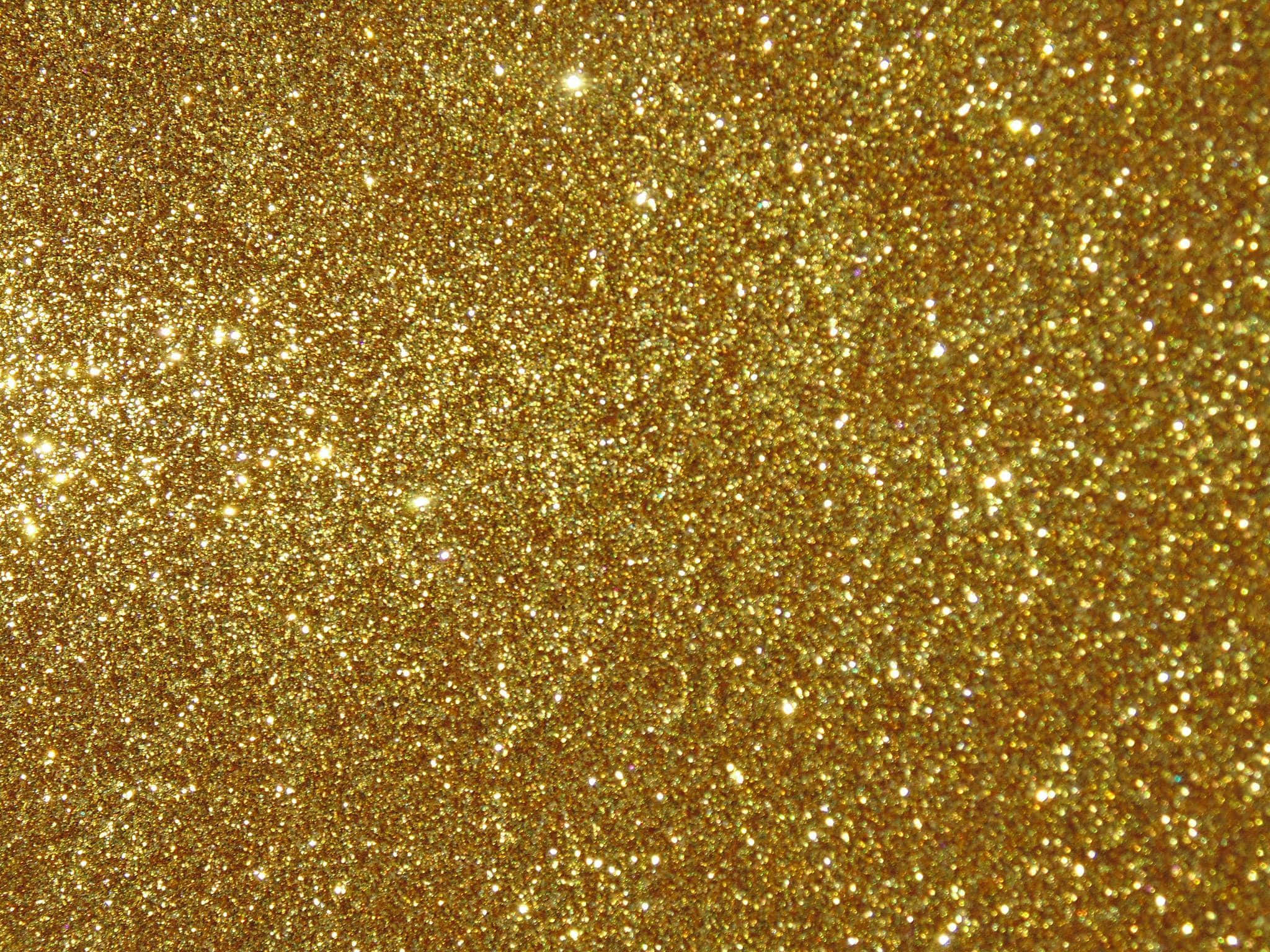 Yellow Glitter 桌布 壁紙 — 密集的金色閃粉在明亮光線下閃爍，營造出閃閃發光的紋理表面。