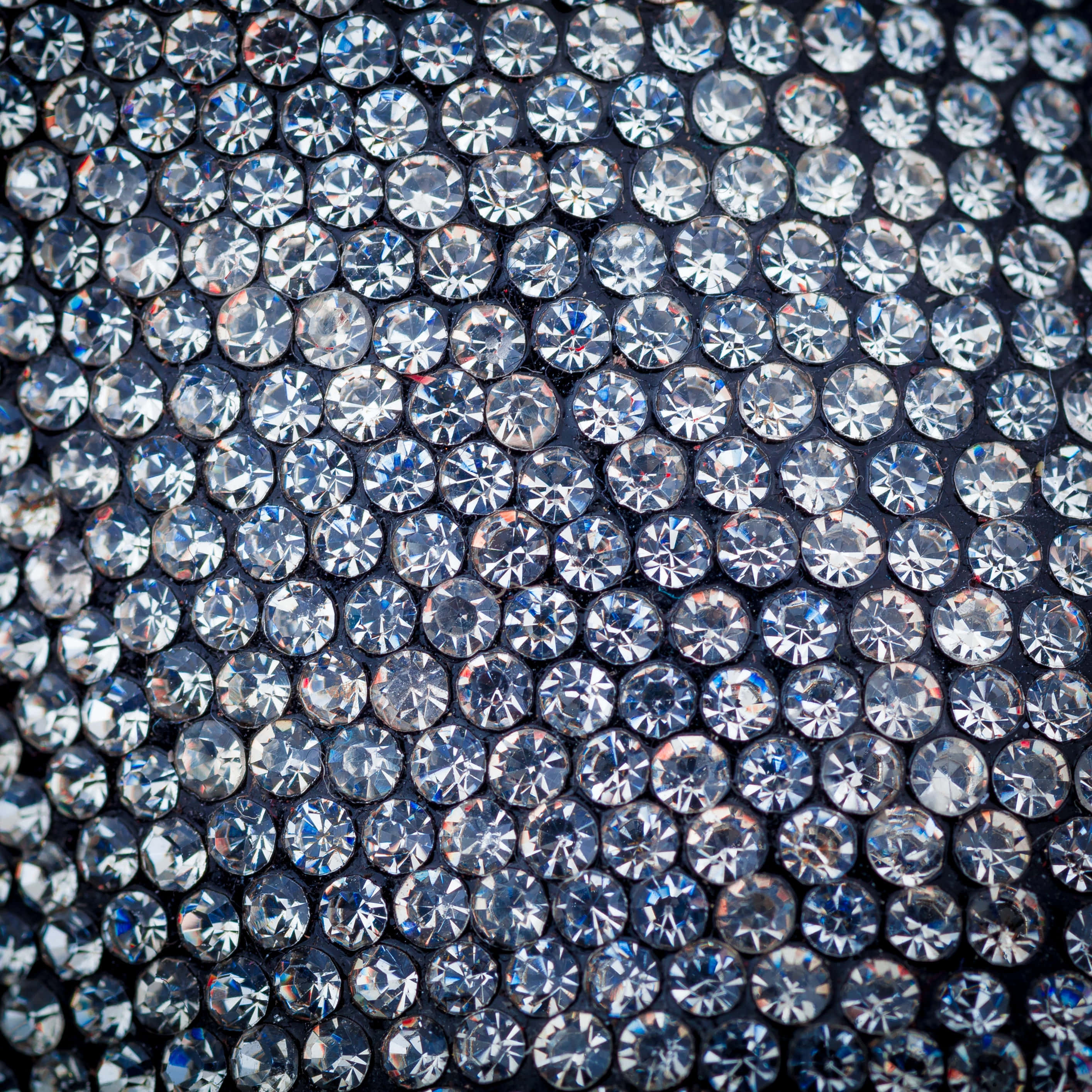 diamonds 桌布 壁紙 — 密集的閃亮透明水鑽在深色表面上捕捉光線，形成耀眼的紋理圖案。