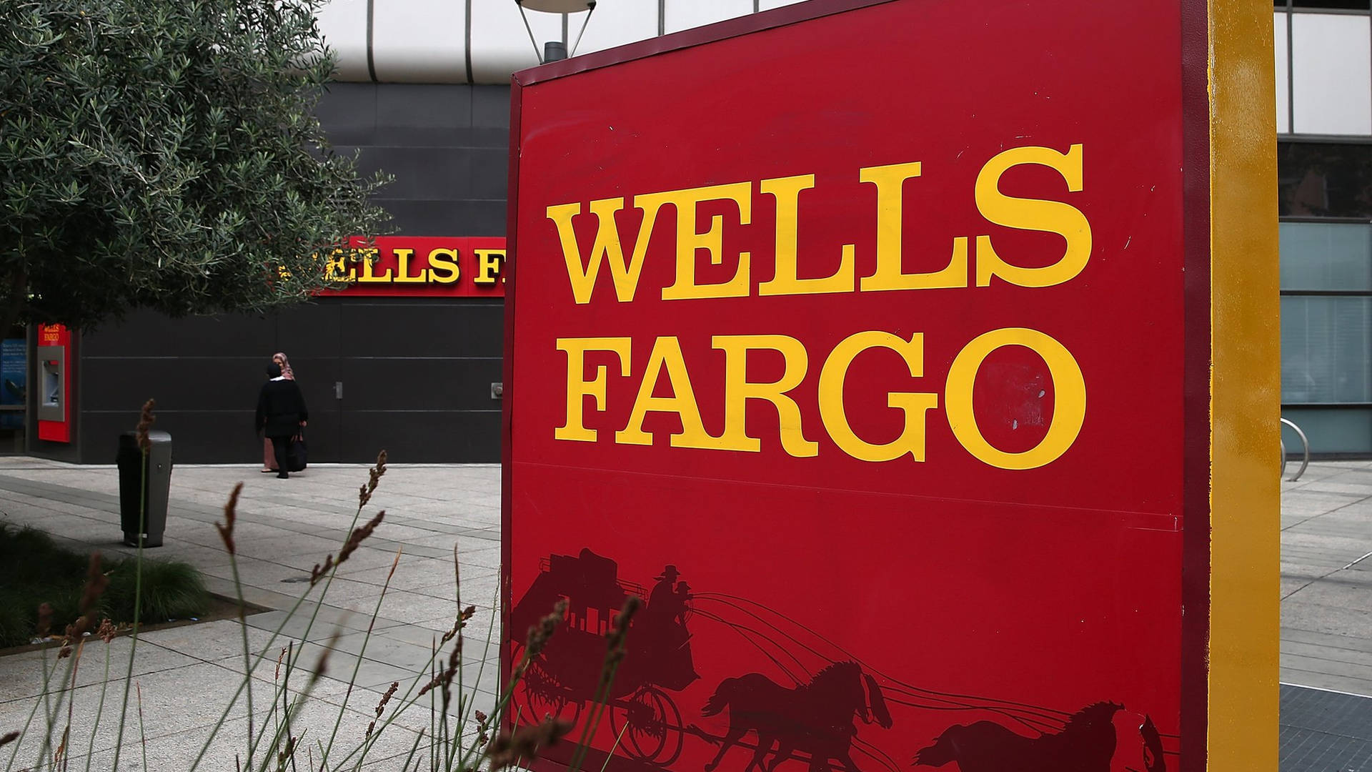 紅色 Wells Fargo 銀行標誌，帶有黃色文字和馬車圖案，位於城市環境中。