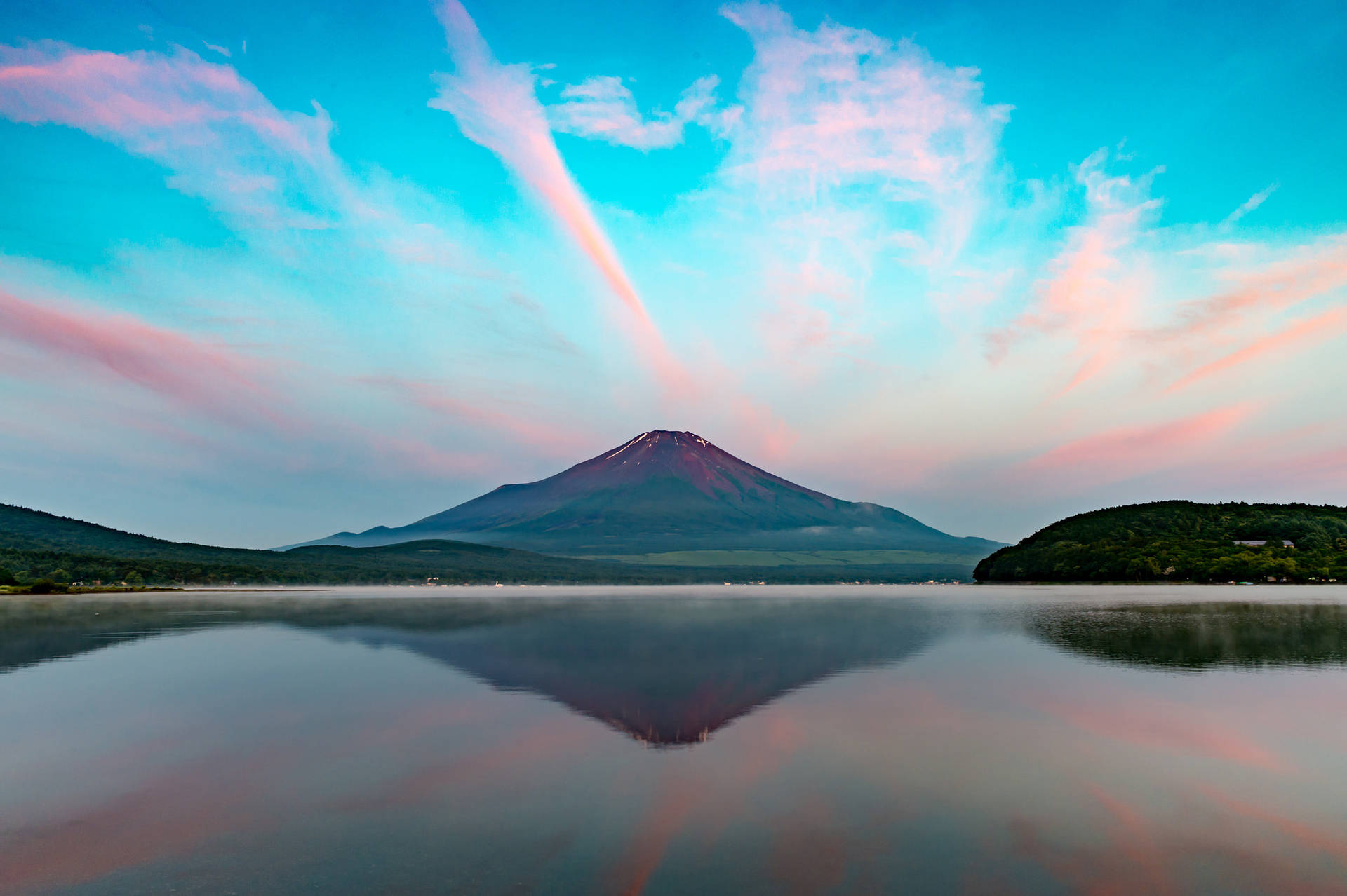 富士山倒映在日落時分的寧靜湖面上，天空呈現粉紅色和藍色。