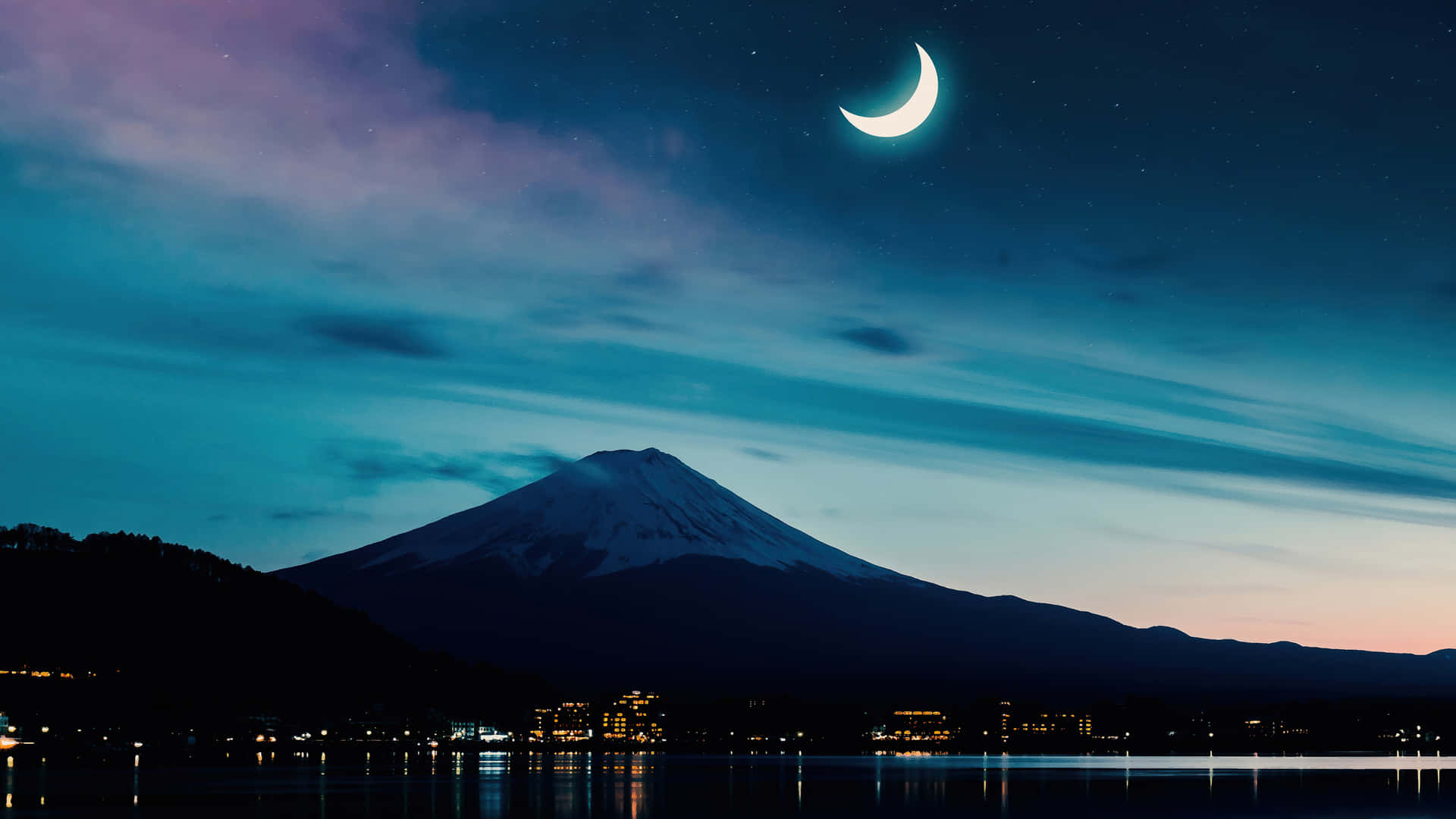 夜晚白雪覆蓋的富士山，新月和小鎮燈光倒映在水中。