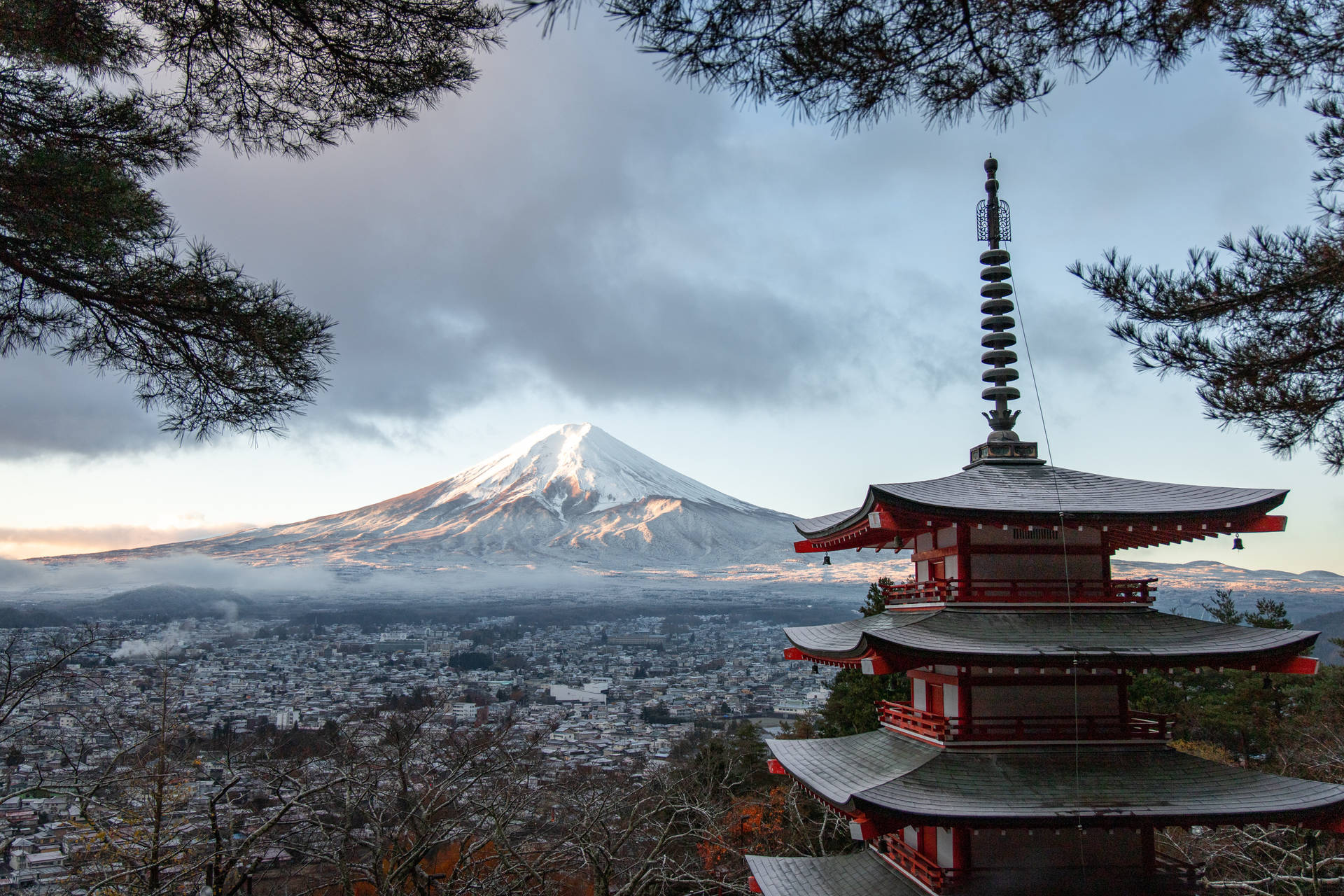 紅色寶塔在黎明時分環繞著城市上空白雪覆蓋的富士山。
