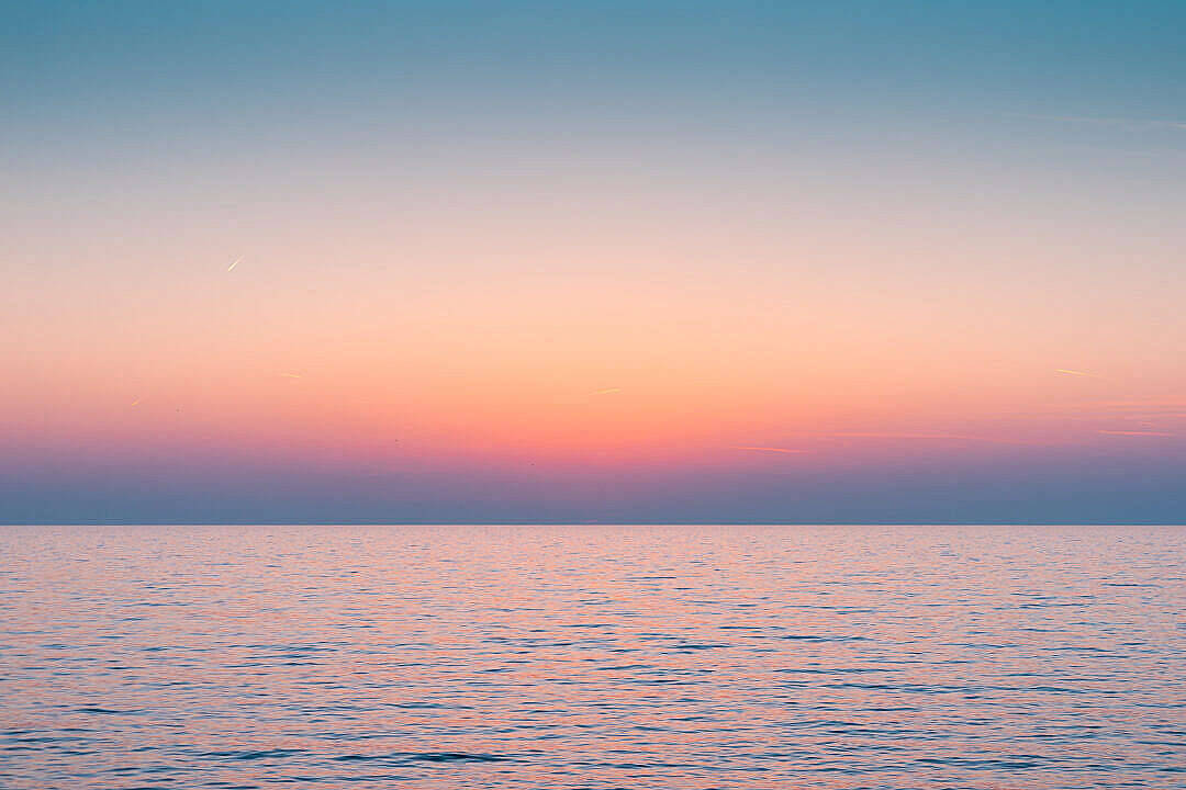 寧靜多彩天空與海平線 壁紙 — 日落時分的寧靜海洋，柔和的粉紅、橙色和藍色色調在地平線上交融。