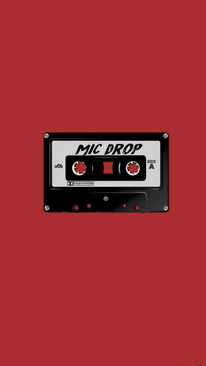寧靜夢幻的紅色美學場景 壁紙 — 一個黑色卡式帶，標有「MIC DROP」，置中於純紅色背景上。