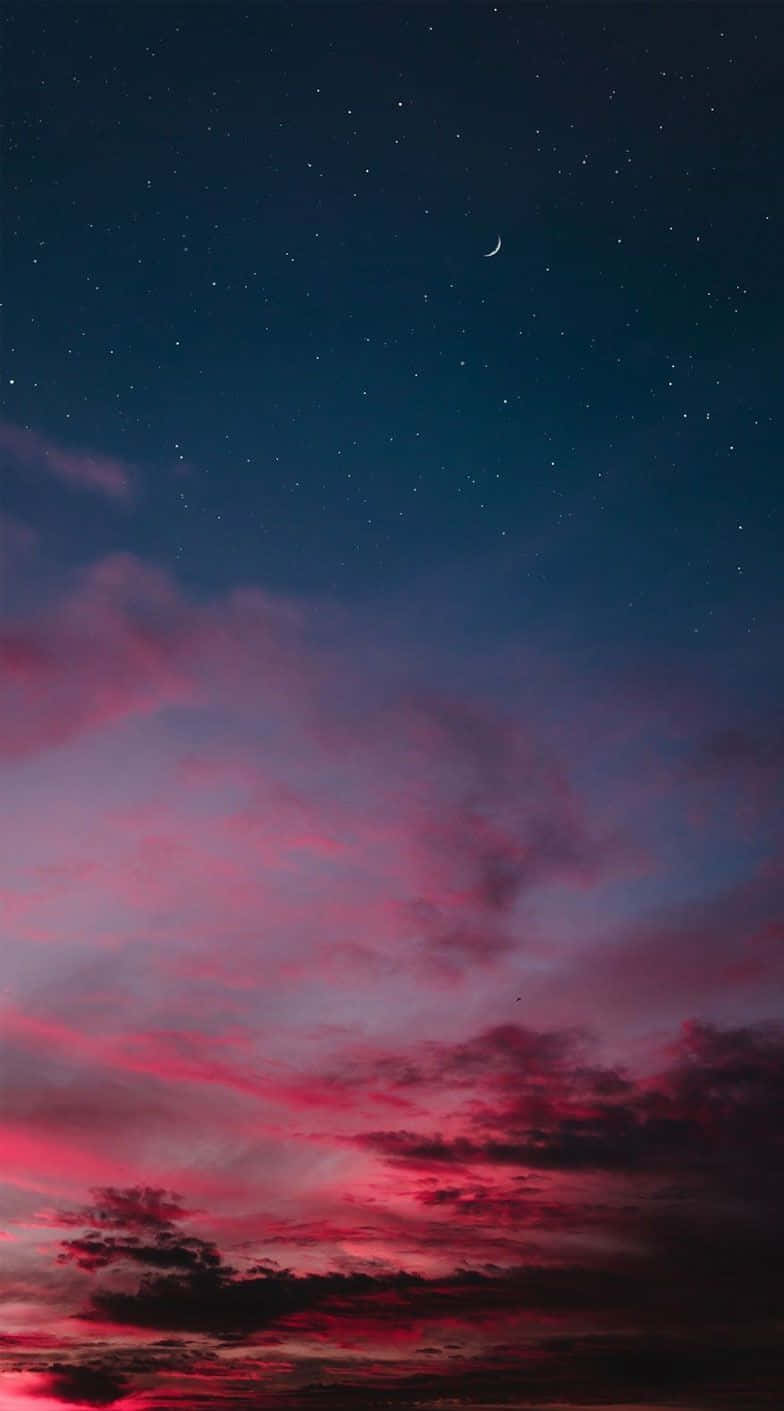 星光閃爍的暮色天空中，鮮豔的粉紅雲彩和一彎新月。