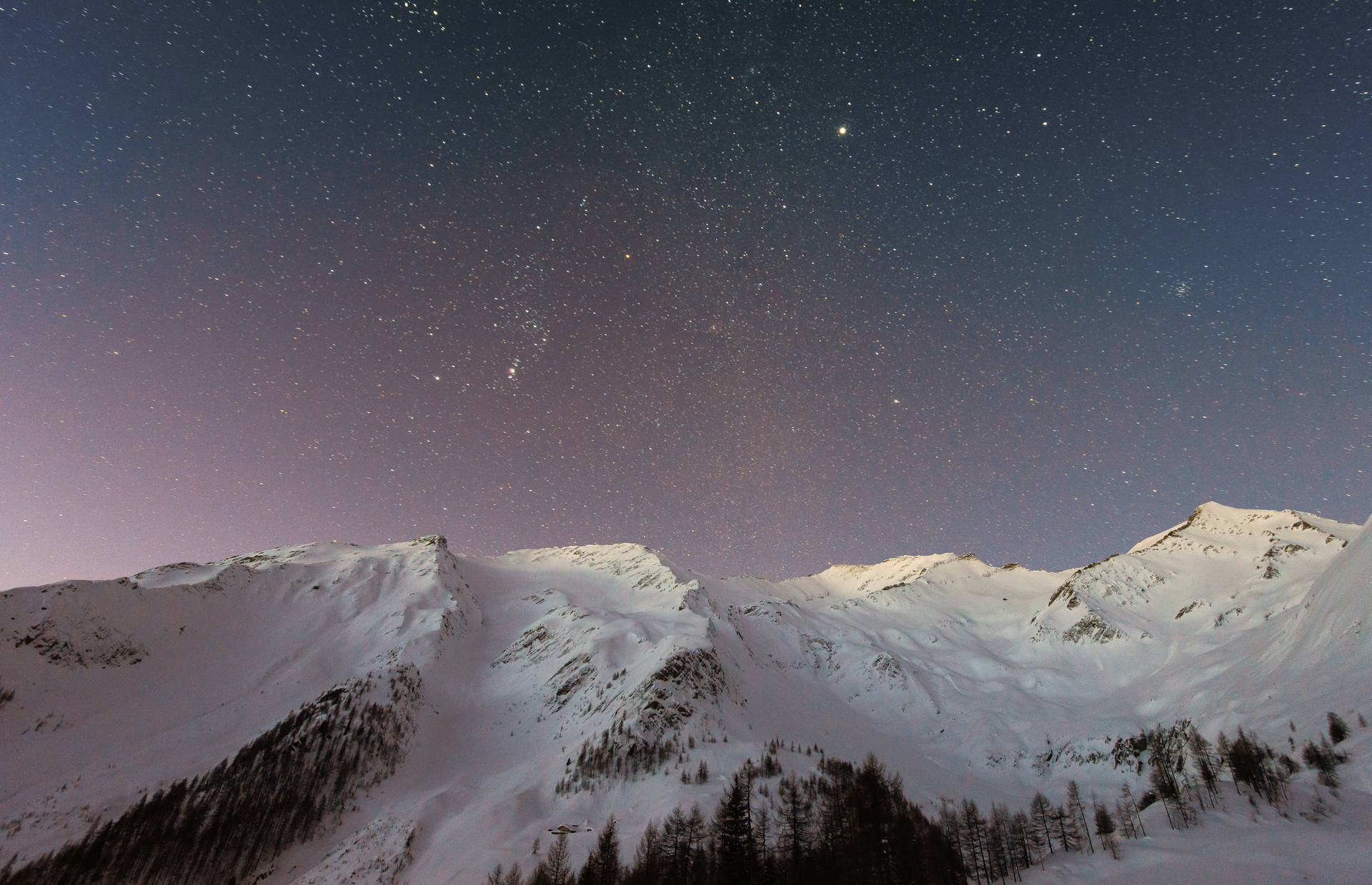 在帶有紫色極光的星空夜空下的積雪山脈。