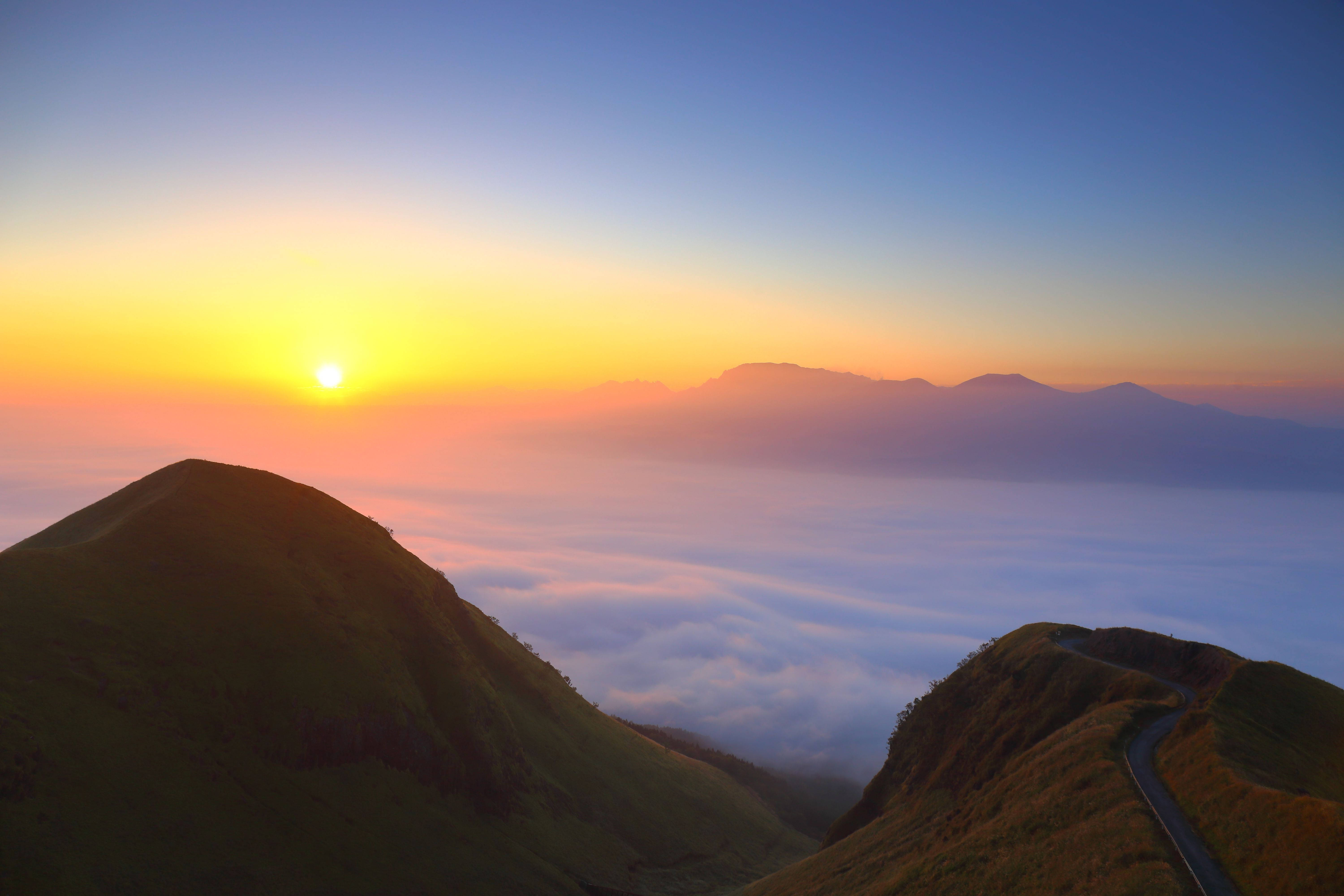 寧靜山景4K 壁紙 — 日出在雲海之上繪出金色天空，下方是蜿蜒的山路。