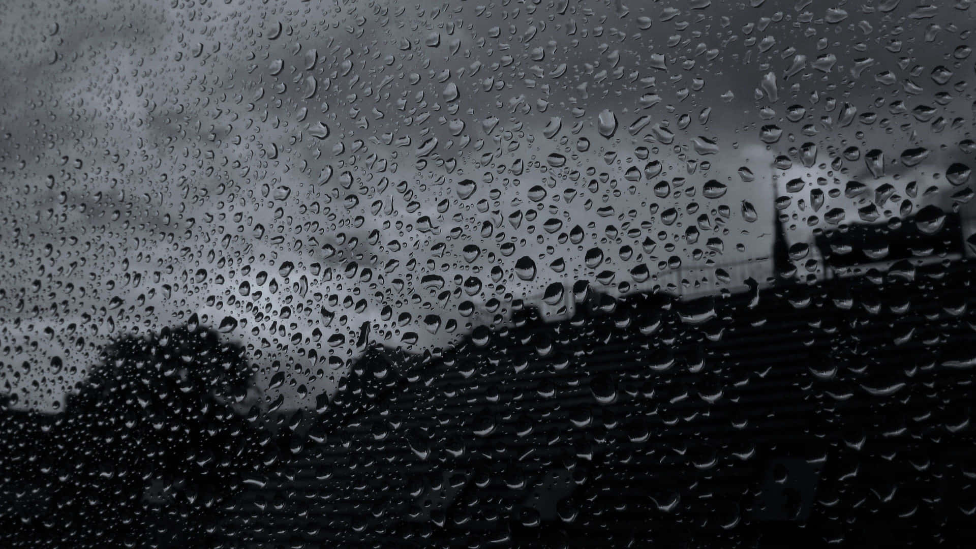 玻璃上的雨滴，背後是黑暗的暴風雲和城市輪廓。