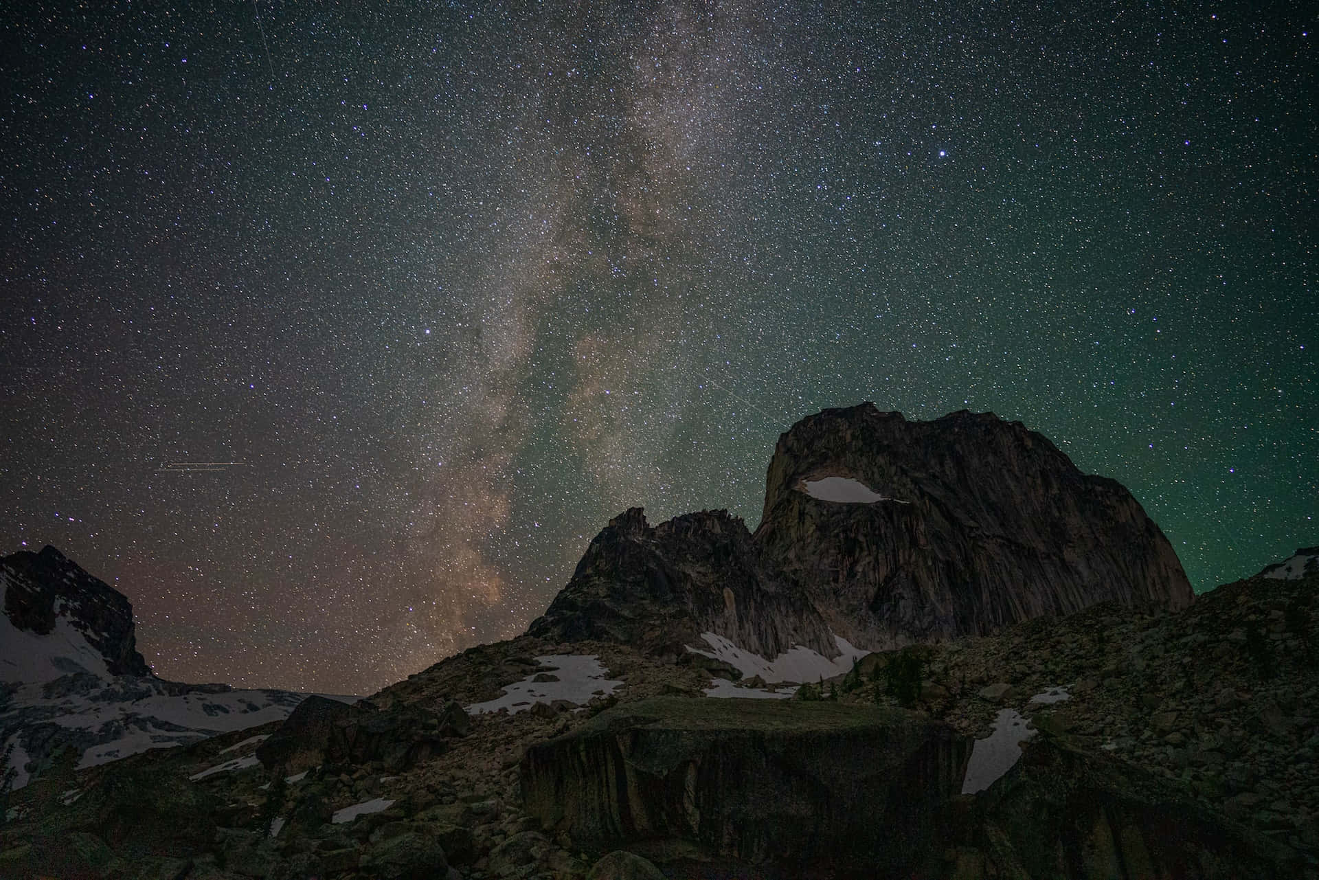 繁星點點的夜空，銀河系在積雪的山峰之上