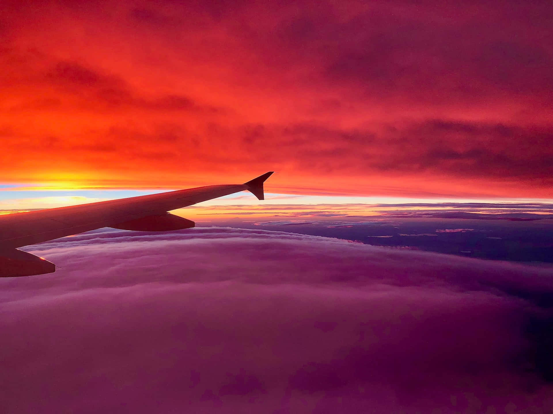 日落時紫色雲層上的飛機機翼