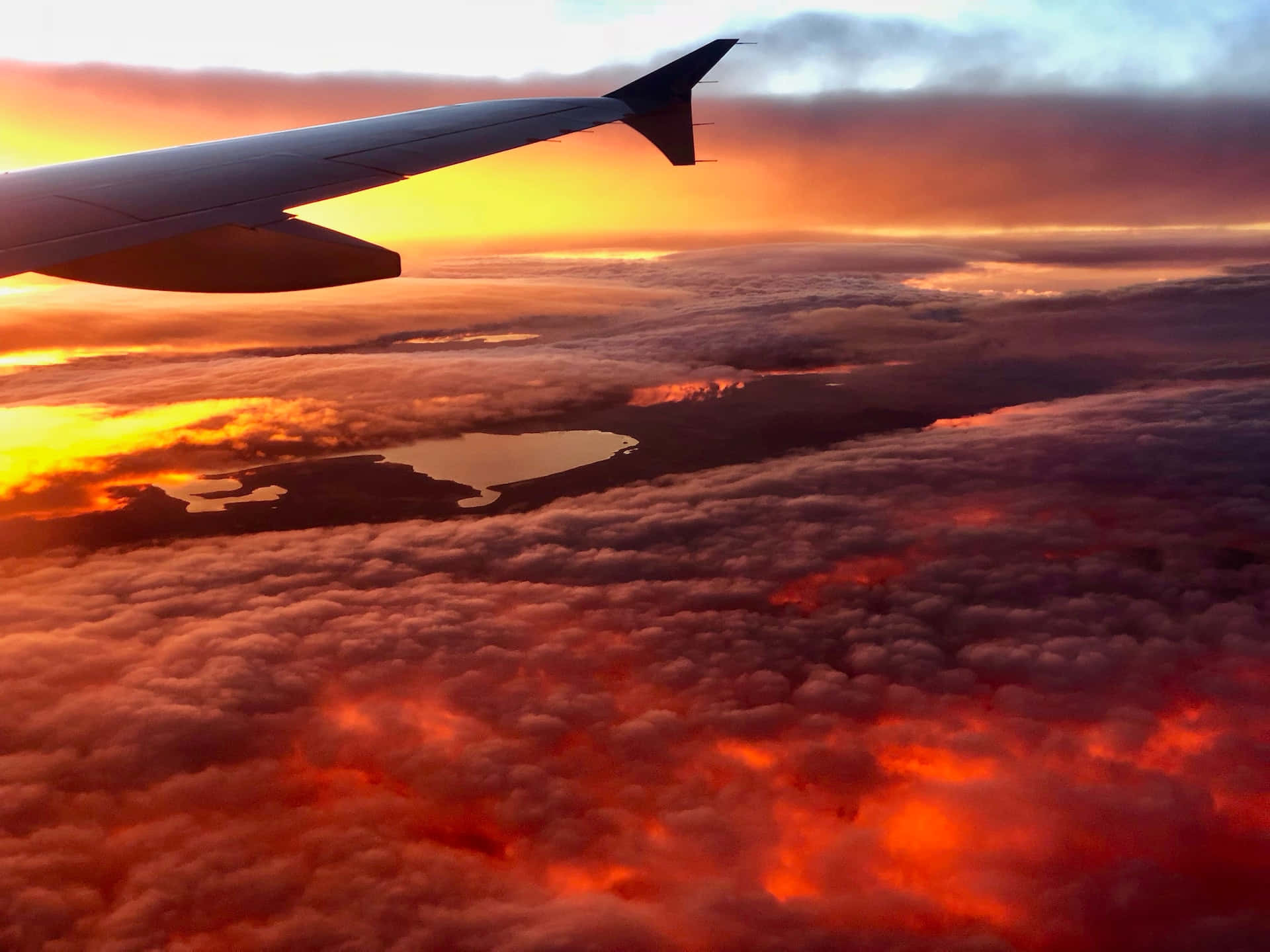飛機機翼在雲層之上，閃爍著夕陽的色彩，照耀著大地。