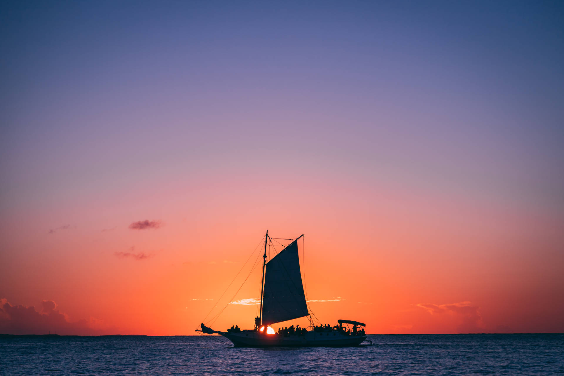帆船上的人們在平靜的海面上欣賞日落。