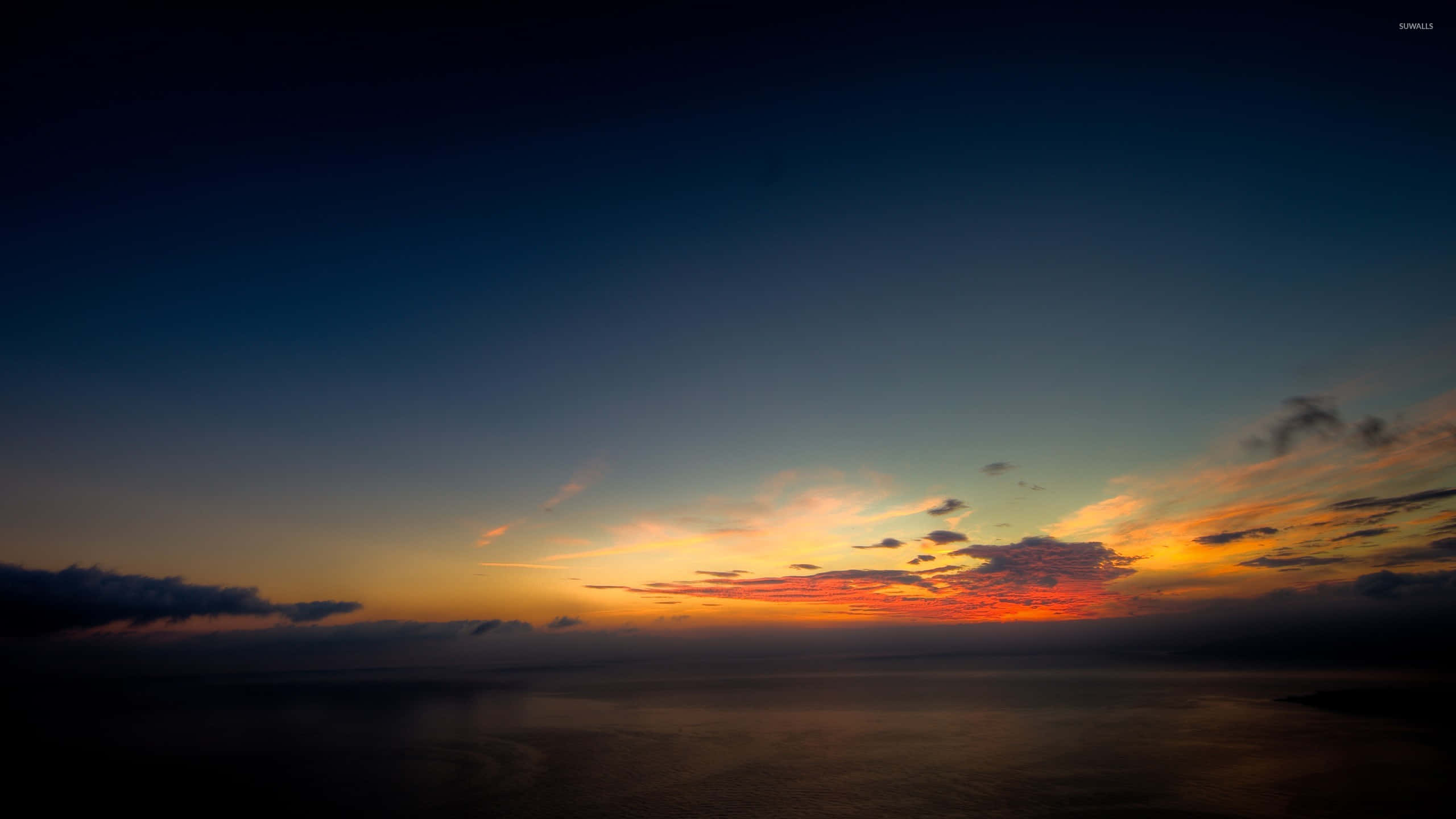 寧靜日落天空風景 壁紙 — 在平靜的海洋上，壯麗的日落，火紅的橙色和紅色雲彩映襯著深藍色的暮色天空。