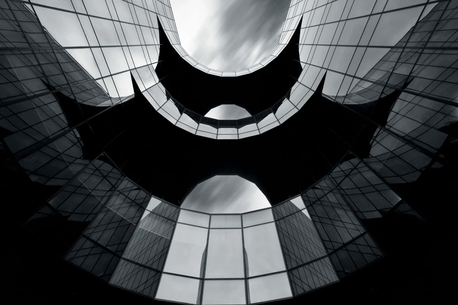 弧形玻璃建築框住天空的黑白建築景觀。