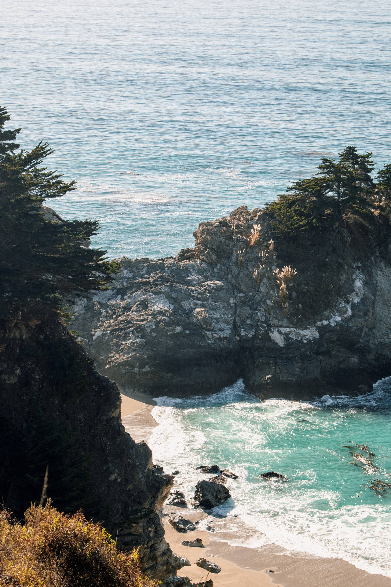 海岸懸崖，碧綠的海浪拍打著沙灘。
