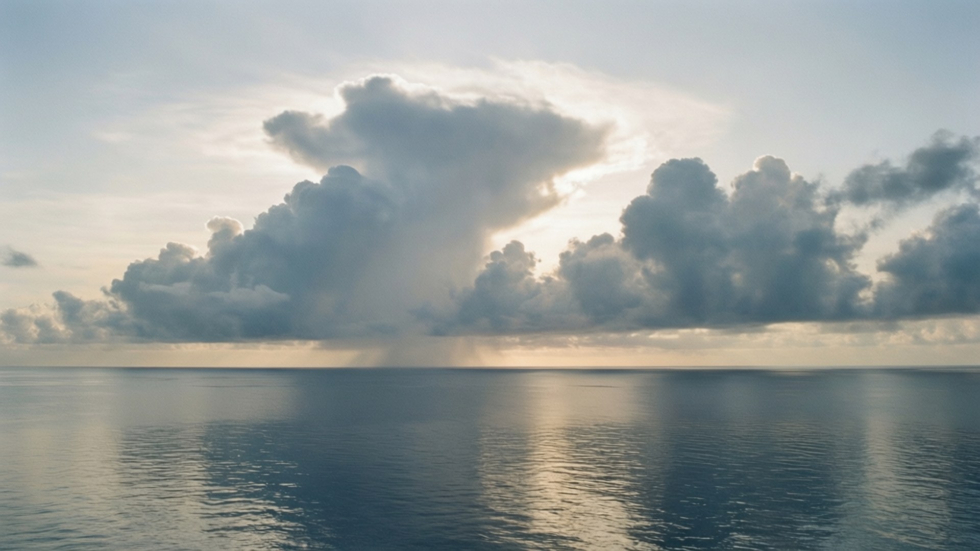 陽光穿過雲層，照耀在平靜的海平線上。
