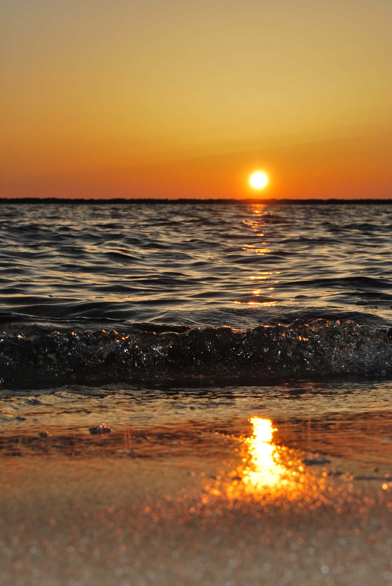海上日落，沙灘上有海浪