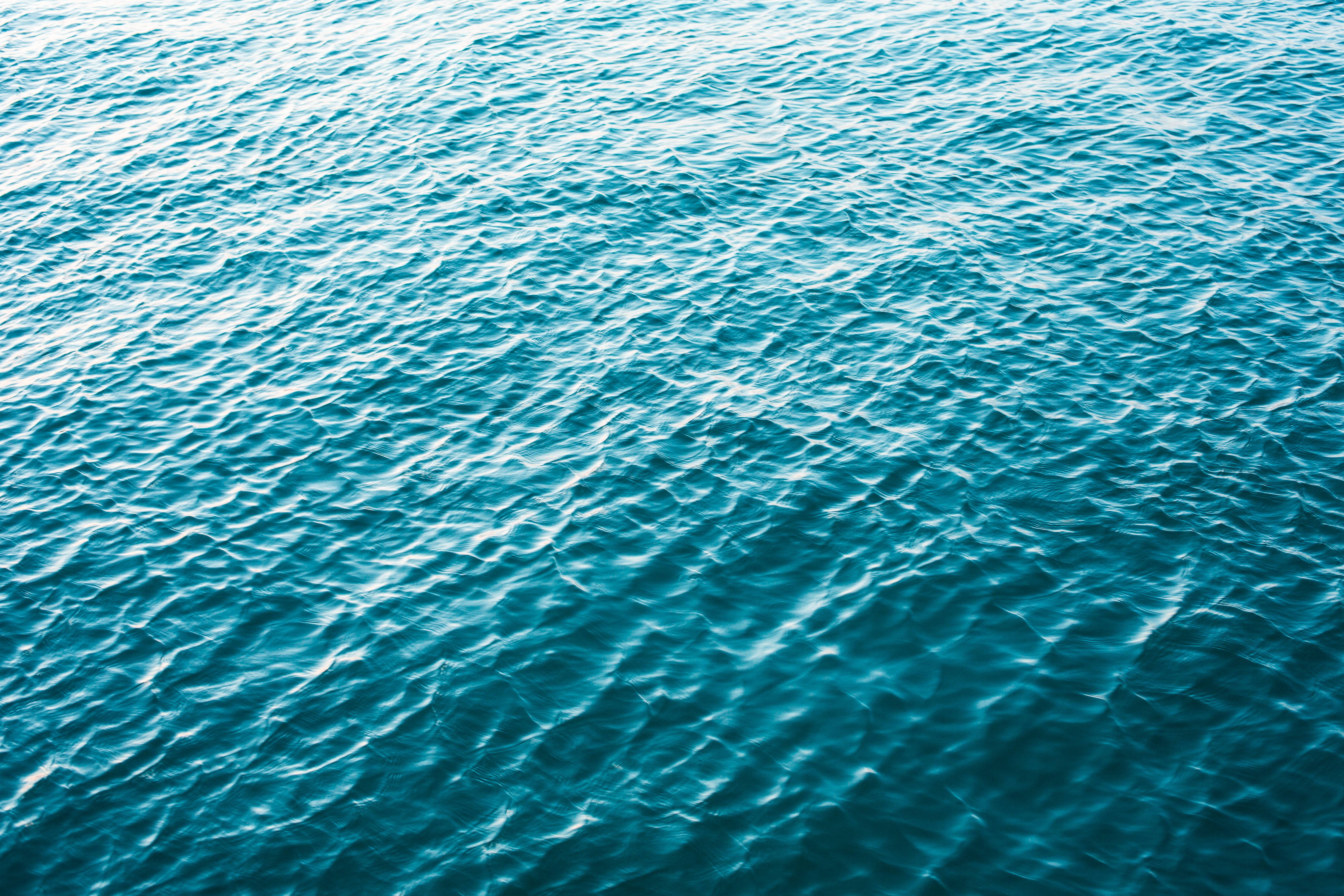 寧靜海面 壁紙 — 特寫視角，呈現紋理豐富的綠松石色海浪在明亮陽光下閃爍。