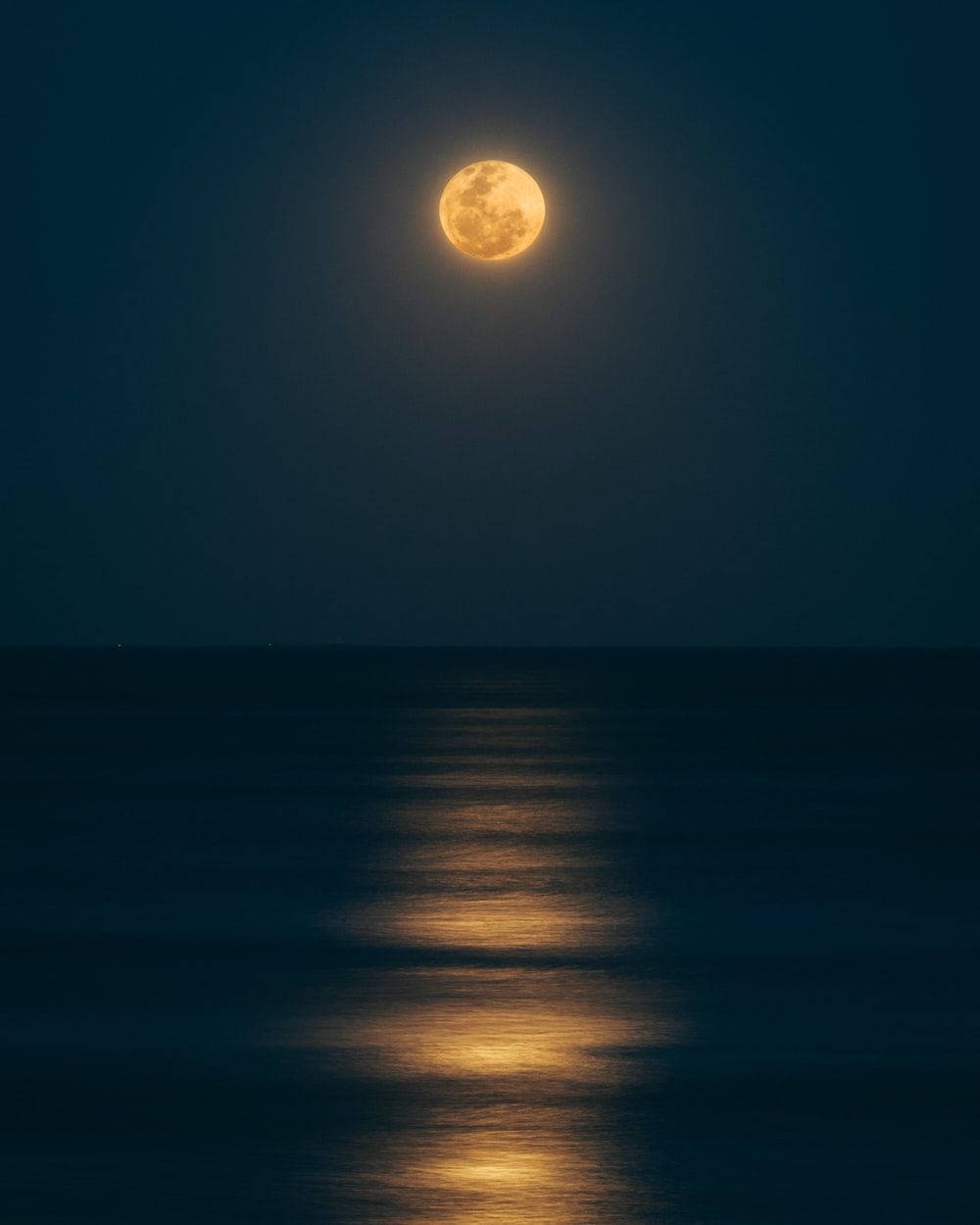 滿月映照在夜間平靜的海洋上