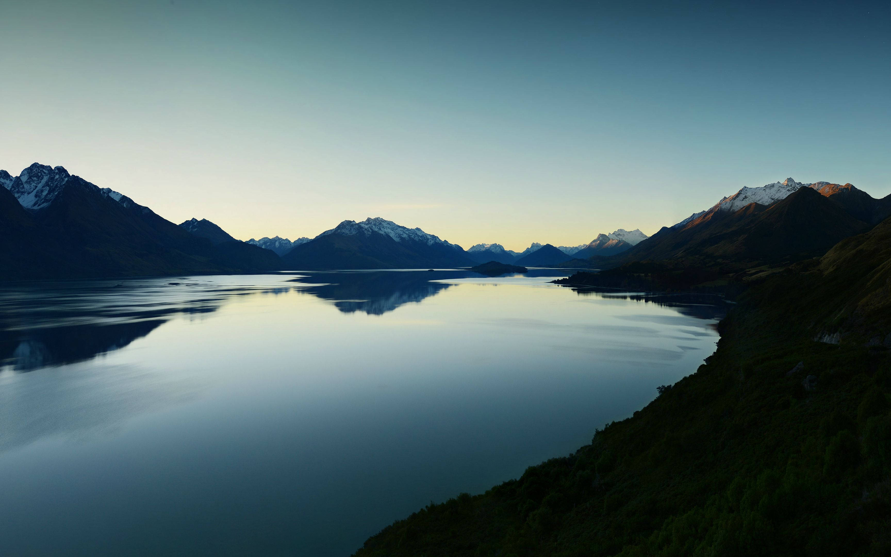 寧靜湖景 MacBook Pro 4K 壁紙 — 寧靜的高山湖泊在柔和漸變色調的暮色天空下，倒映著積雪的山峰。