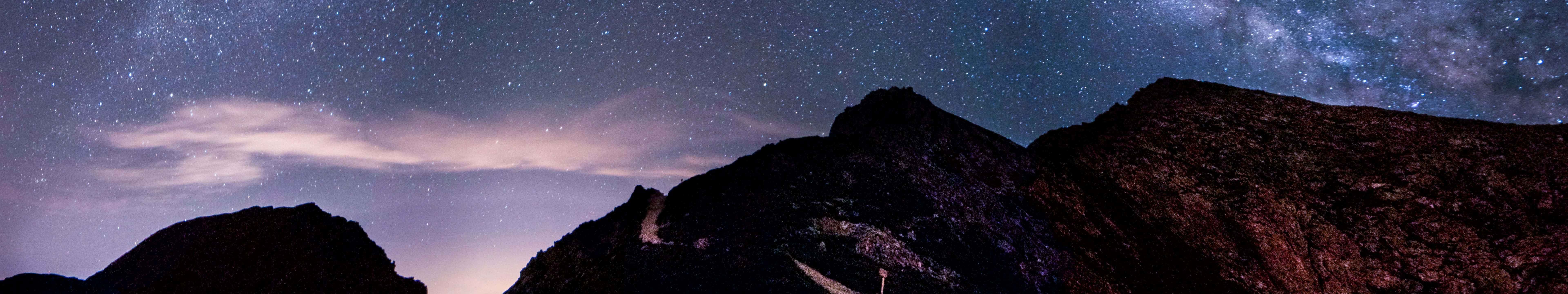 在充滿活力的星空夜空下，黑暗的山峰，銀河可見。