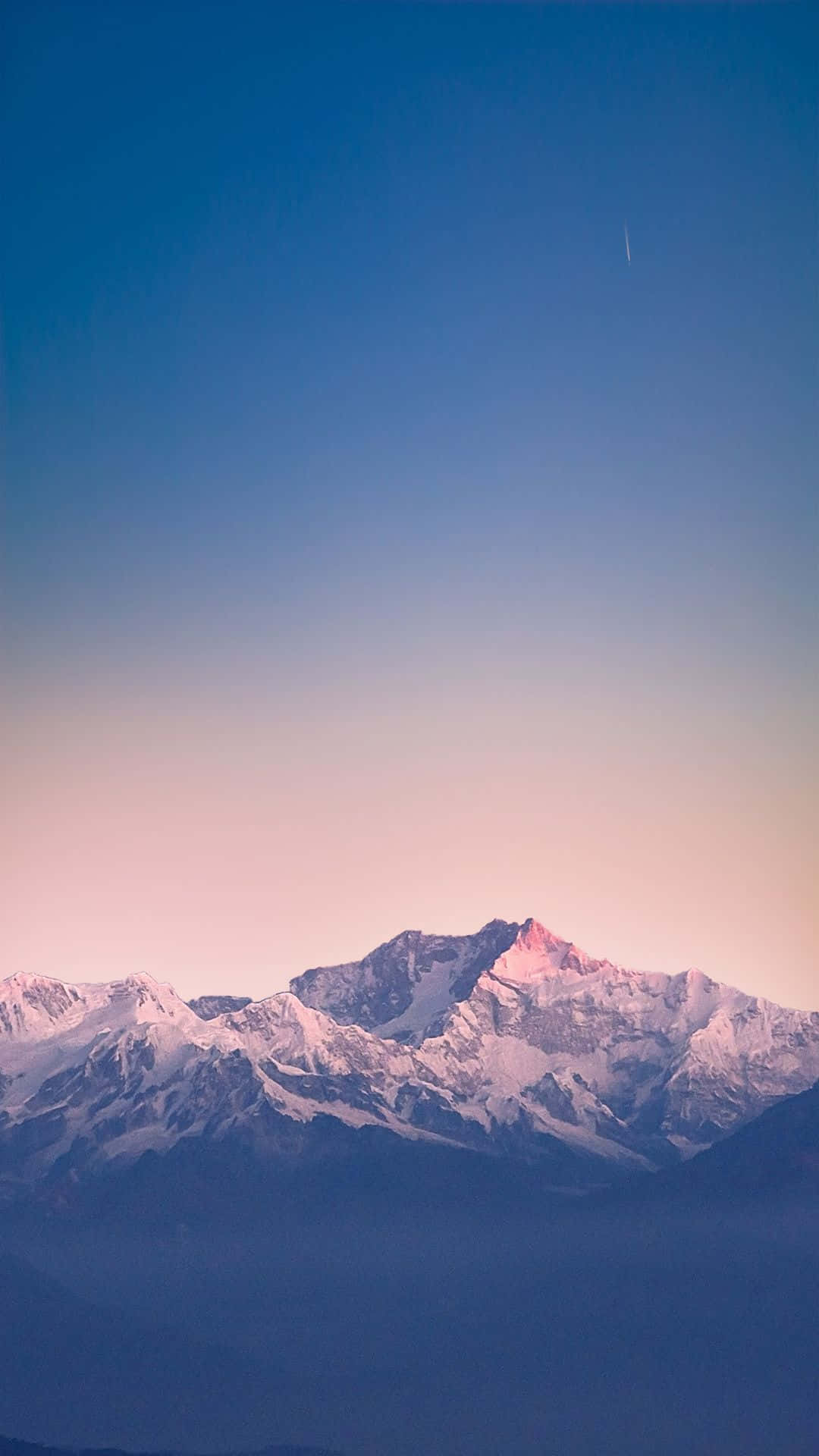 白雪皚皚的山脈在清澈的藍天下沐浴在粉紅色的黎明光芒中。