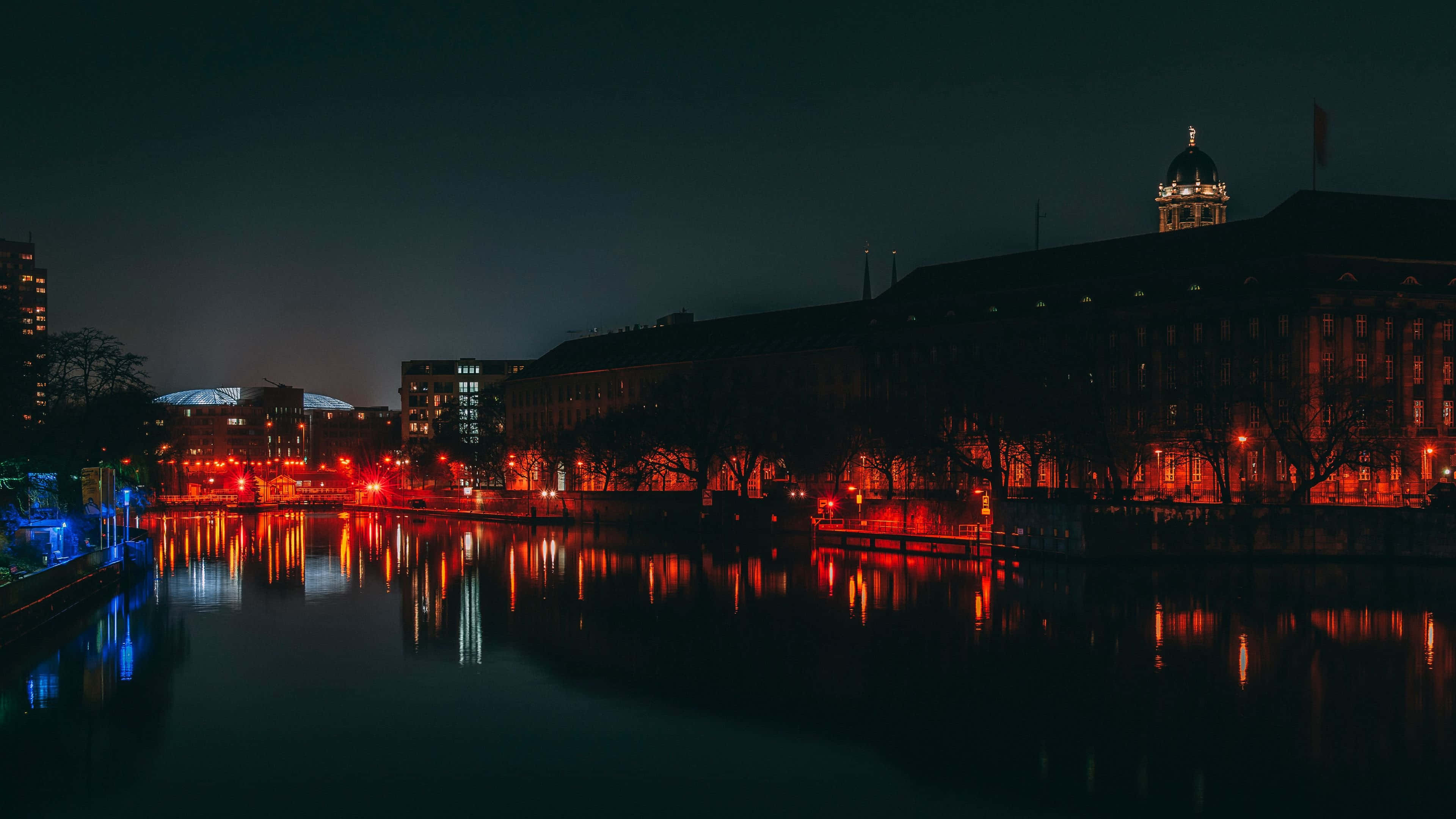 Germany 桌布 壁紙 — 寧靜的夜景，溫暖的紅燈映照在歷史建築旁的平靜水面上。