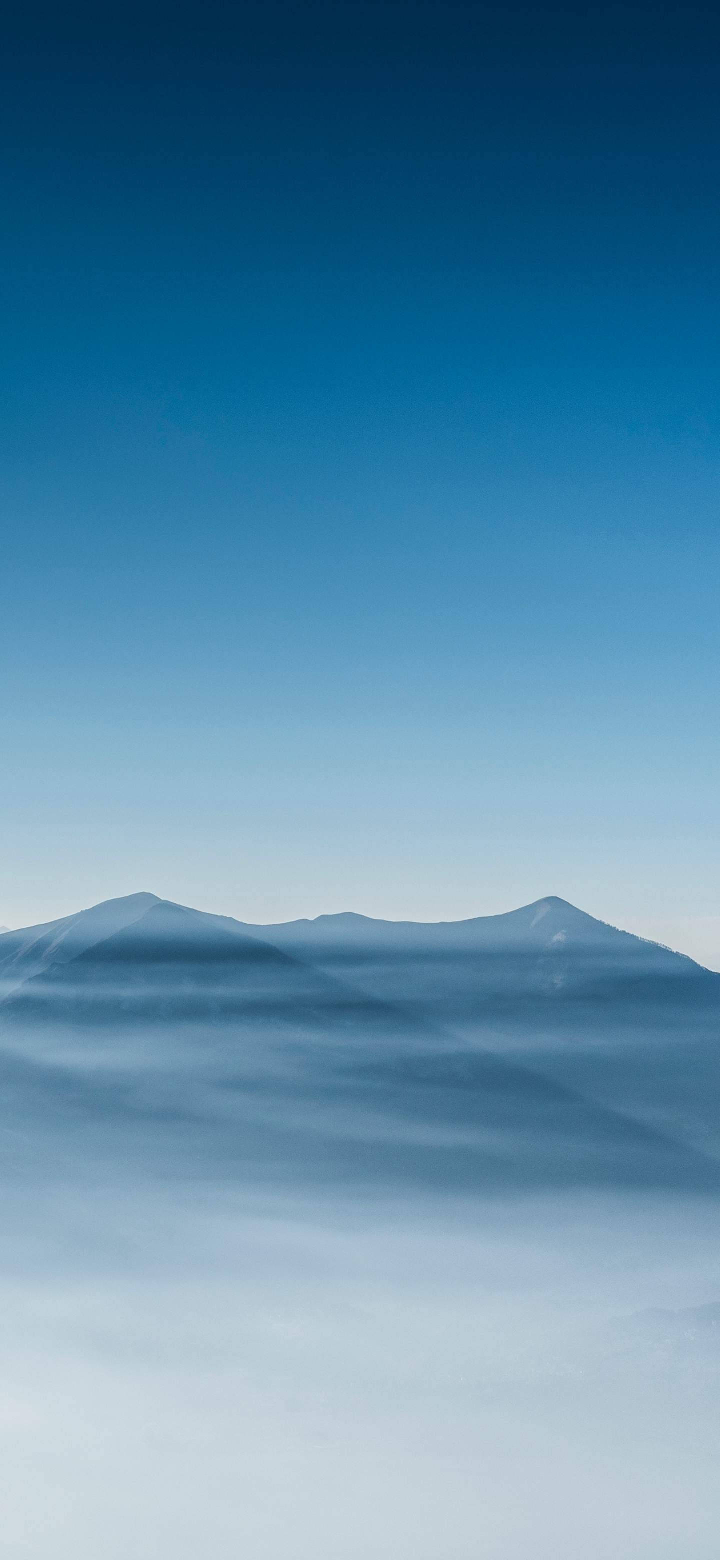 山脈 桌布 壁紙 — 寧靜的山峰在漸變藍天下從霧海中升起。