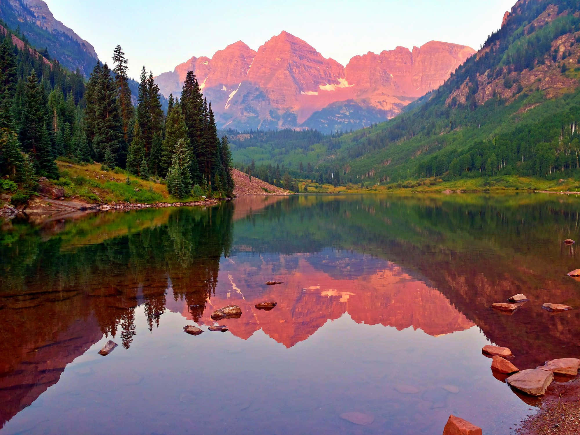 Colorado 桌布 壁紙 — 寧靜的山間湖泊映照出日落時分粉紅色的山峰和常綠樹木。