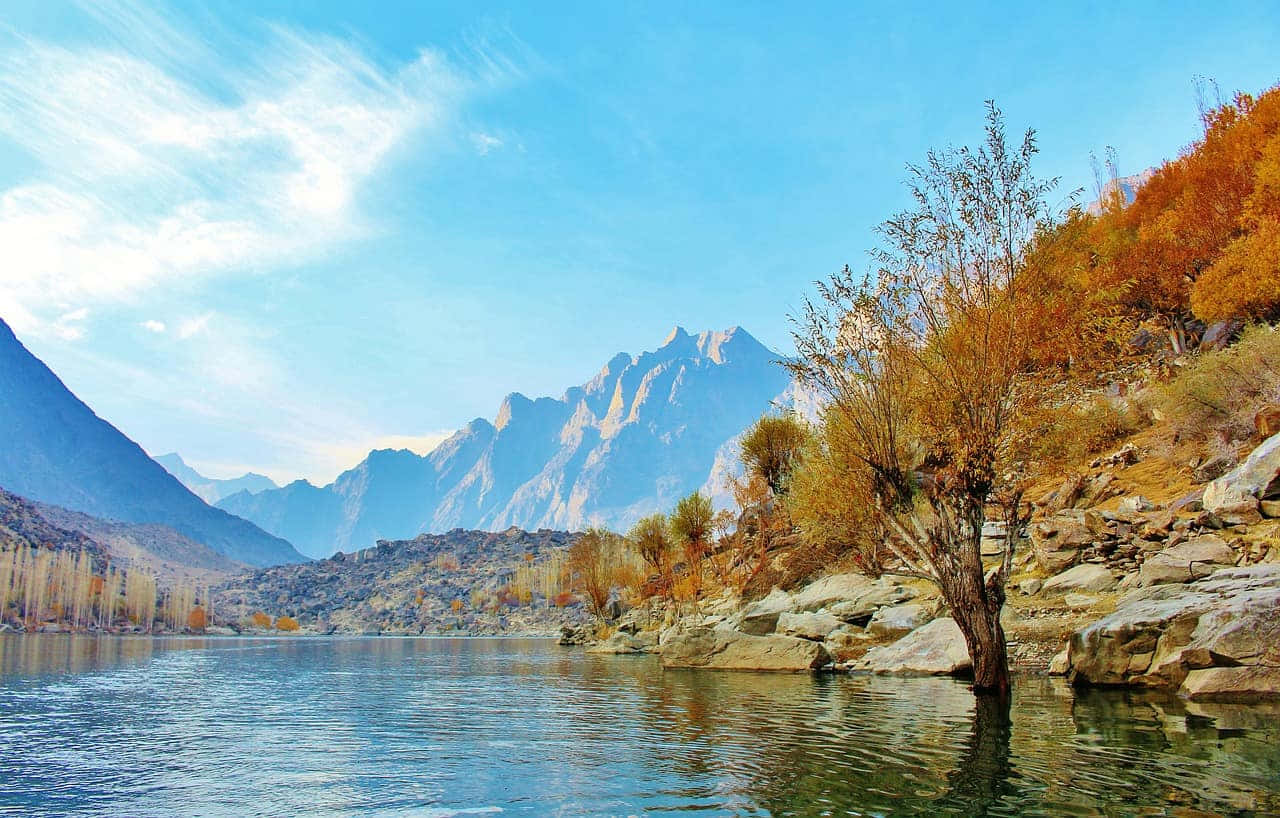 Pakistan 桌布 壁紙 — 寧靜的山間湖泊映照著清澈的藍天和依附在岩石岸邊的秋日樹木。