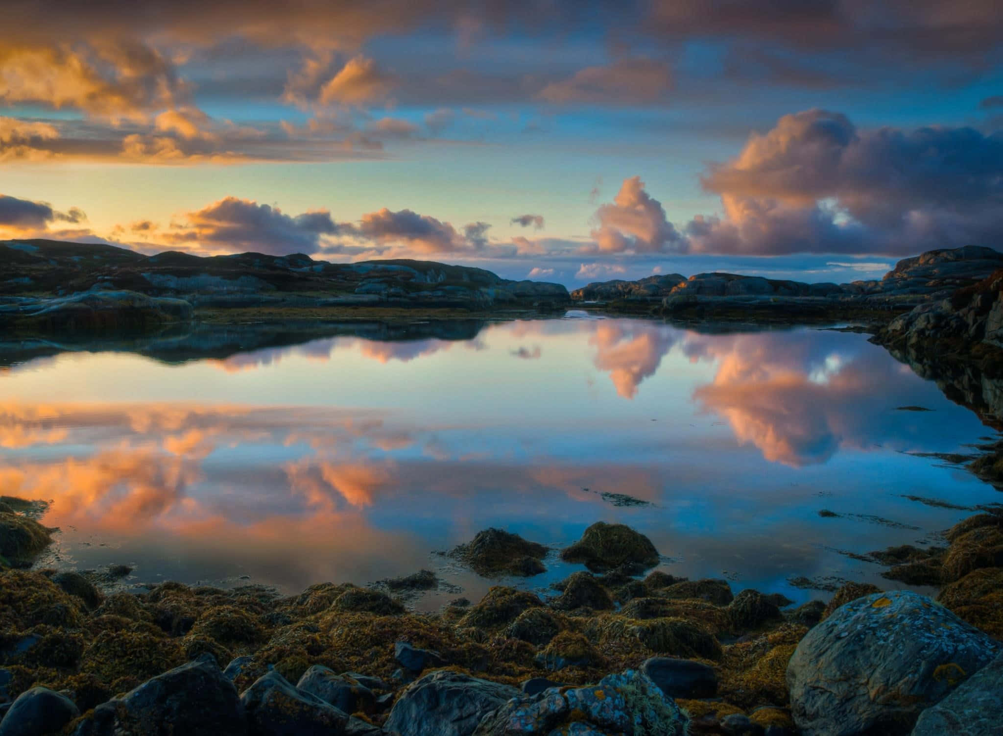 Sunset Reflection 桌布 壁紙 — 寧靜的暮色湖泊映照著崎嶇岩石海岸上如火般的橙色和深藍色雲彩。