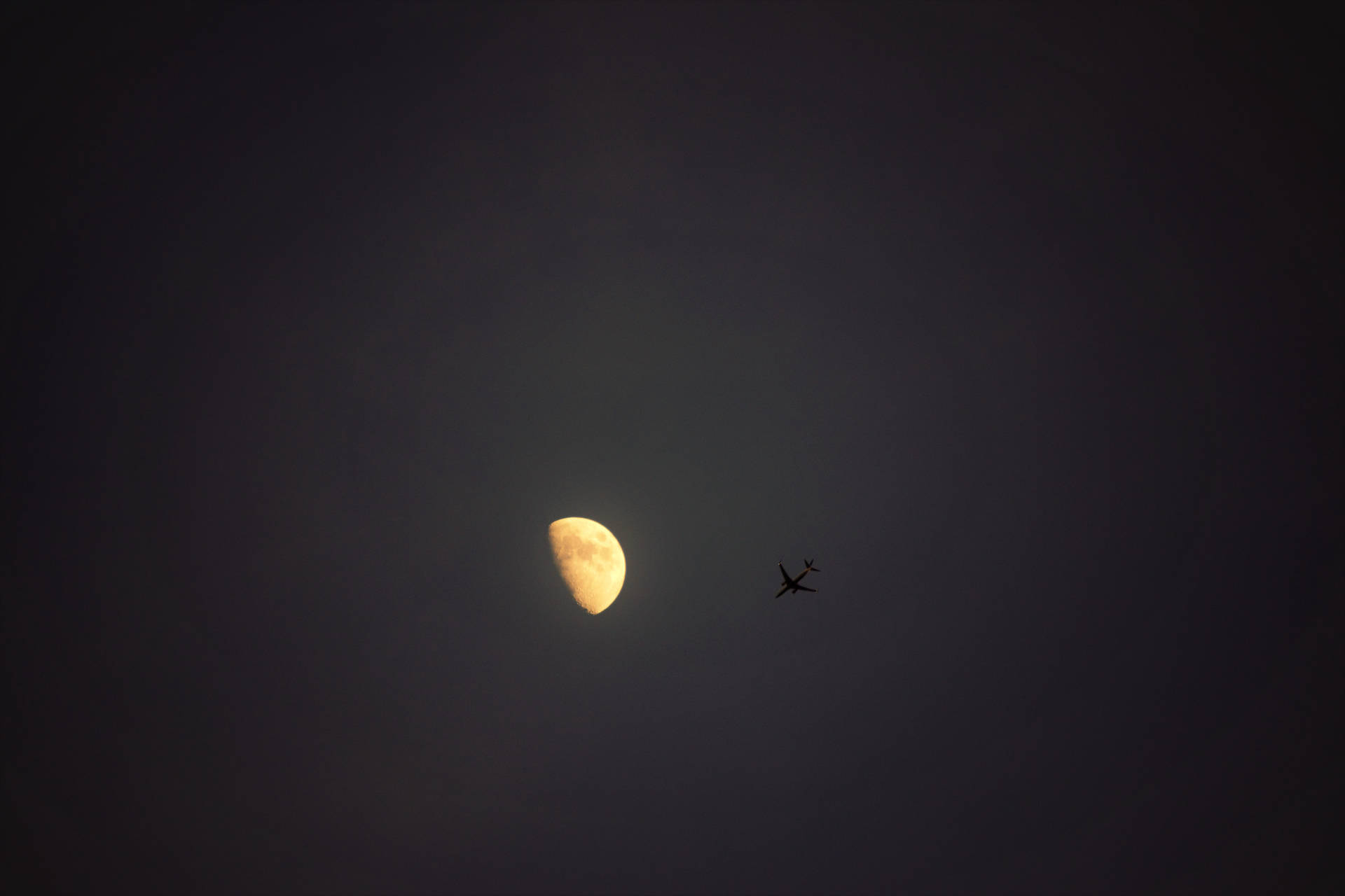 一彎新月與附近飛過的小飛機在夜空中的景象。