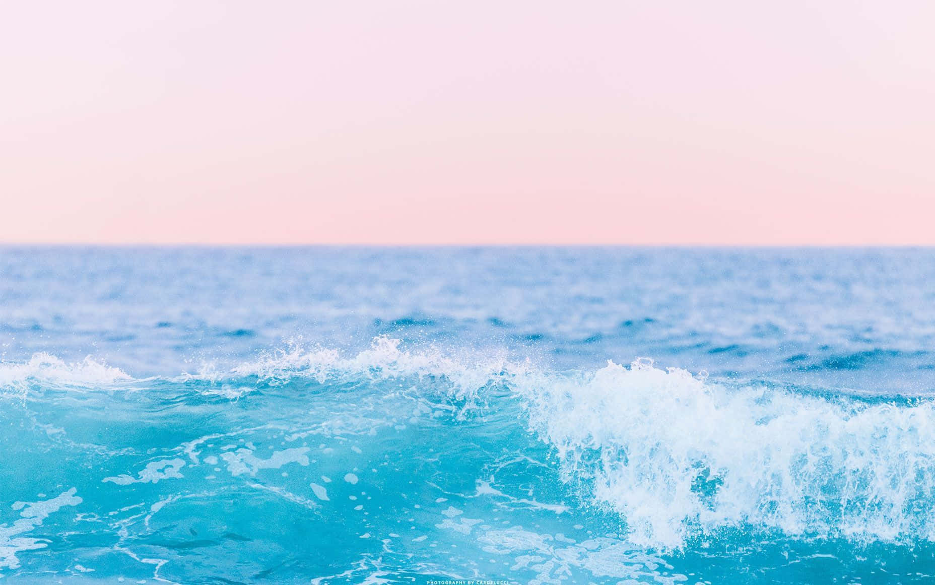 寧靜的海景 壁紙 — 在日落時分，一道藍綠色的海浪帶著白色泡沫拍打著柔和的粉紅色和藍色天空。
