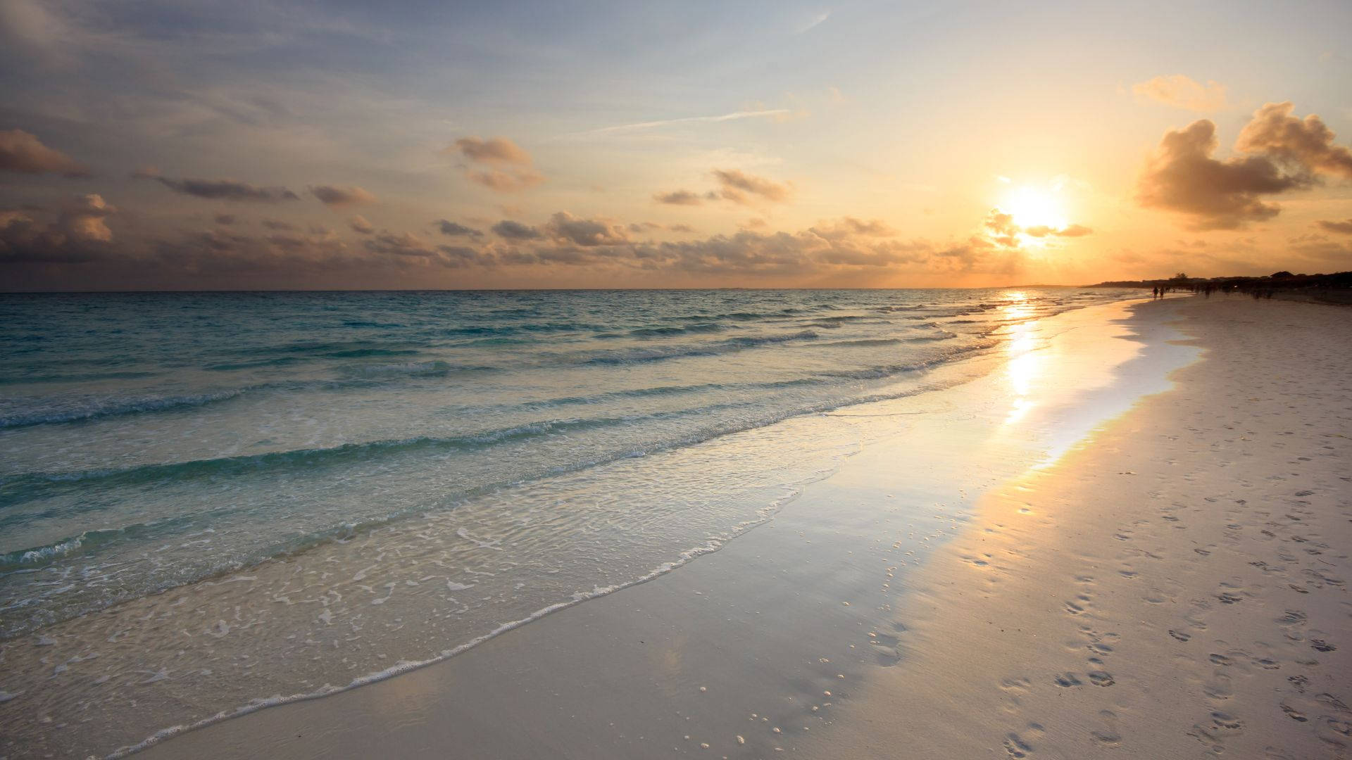 夕陽下的海洋，輕柔的海浪和沙灘上的腳印
