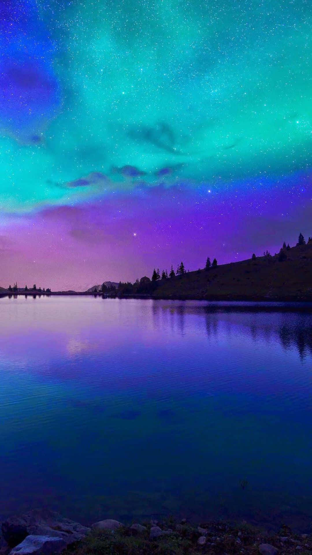 iPhone 8 Plus 桌布 壁紙 — 寧靜的湖面映照著在遙遠山丘上、繁星點點的紫色和青色天空中舞動的極光。