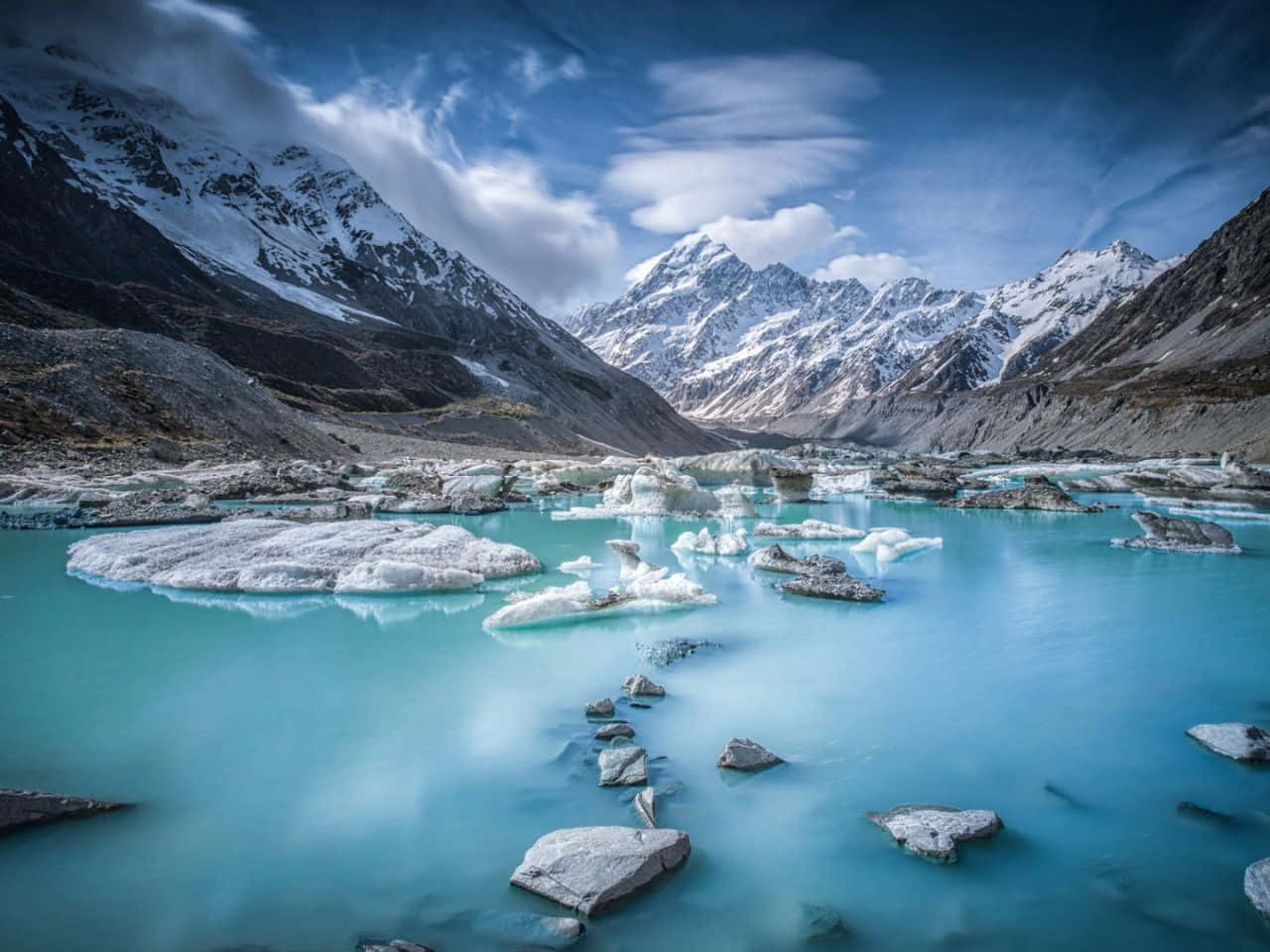 寧靜的鄉村日落 壁紙 — 一個寧靜的冰川湖，湖水碧綠，漂浮著冰山，四周被白雪覆蓋的山脈環繞，天空壯麗。