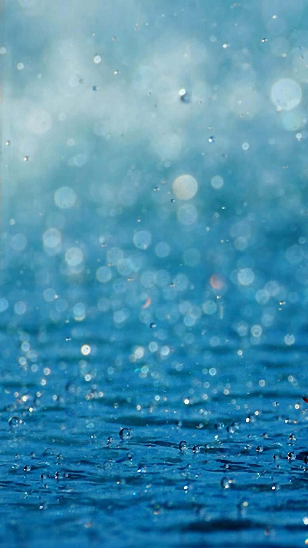 雨滴在藍色水面上營造出閃閃發光的散景。