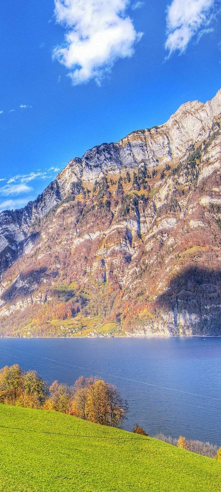 Mountain 桌布 壁紙 — 寧靜的高山湖映照著高聳的岩石峭壁，點綴著秋葉，在明亮的藍天白雲下。